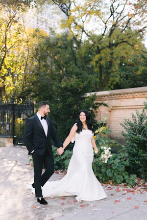 Bride with groom wearing strapless satin mermaid wedding dress with big bow on the back.
