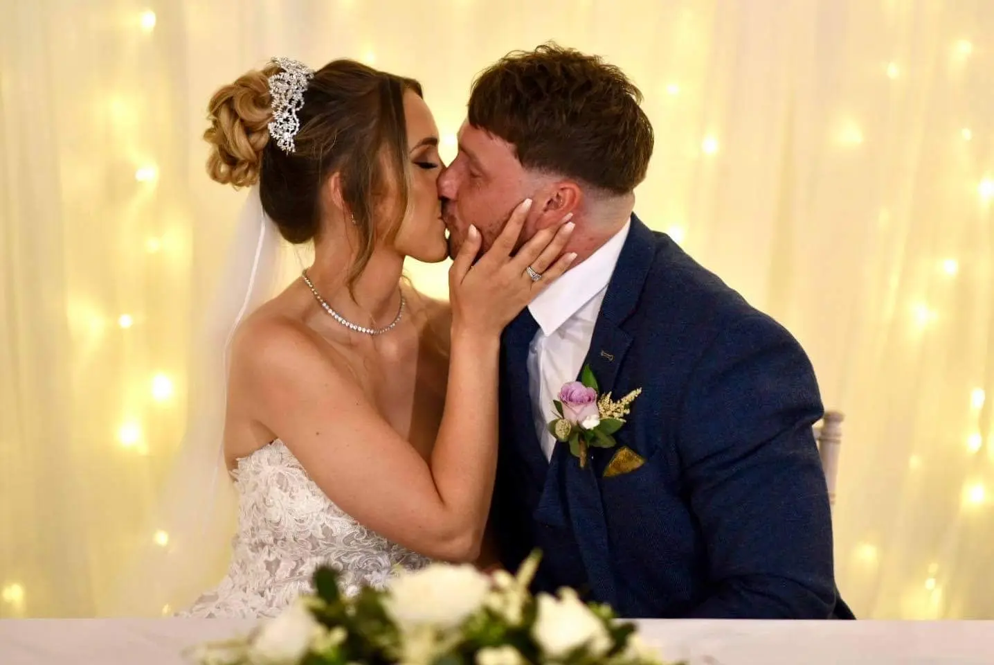 bride kissing groom in lacy mermaid wedding dress