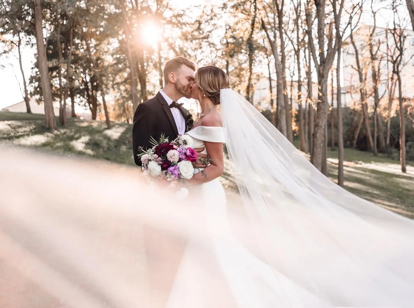 Groom Kissing Bride In Long Veil And Off The Shoulder Wedding Dress Named Josie By Rebecca Ingram