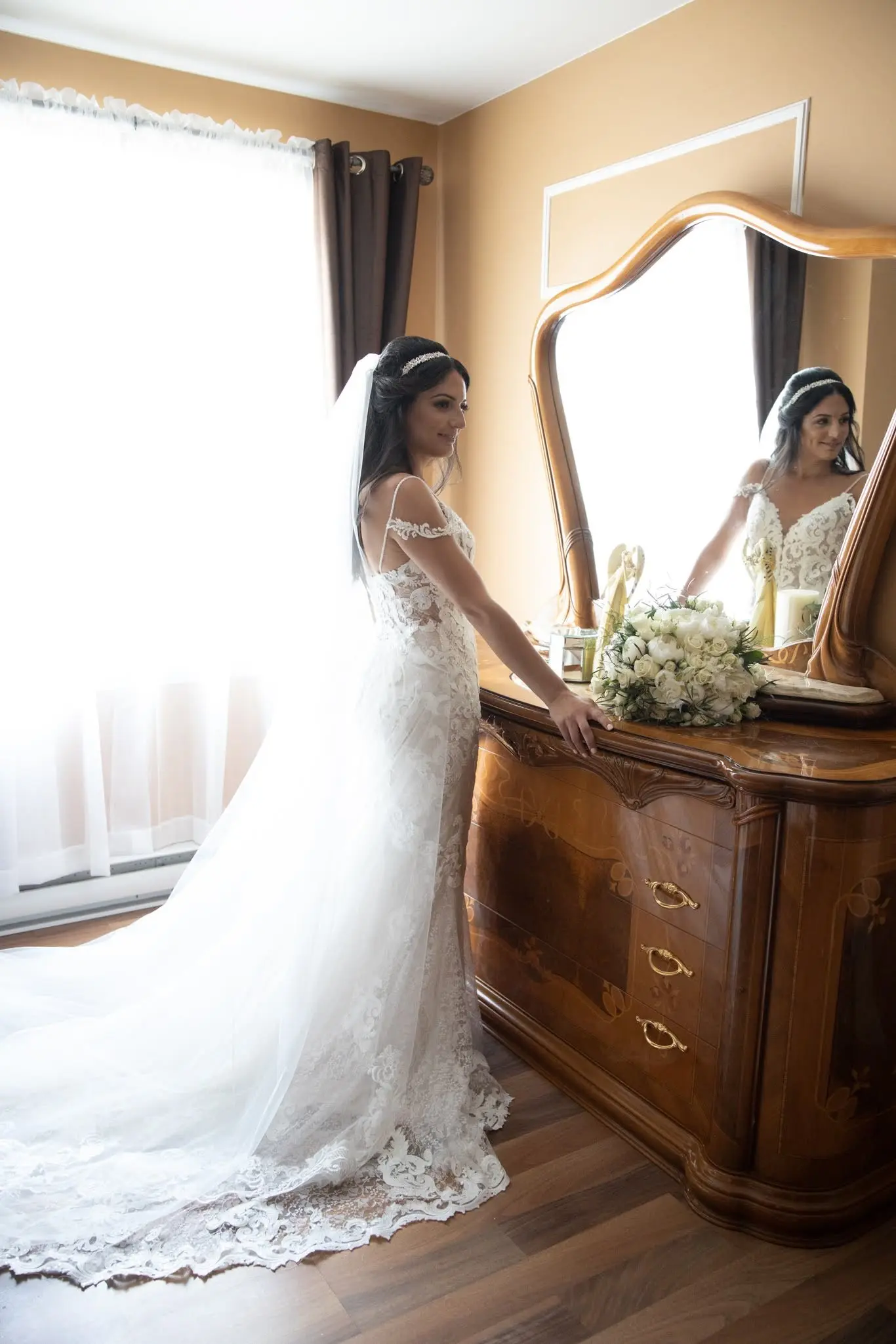 Bride Wearing Lace Sheath Wedding Dress Called Tuscany Lynette By Maggie Sottero Standing By A Vanity