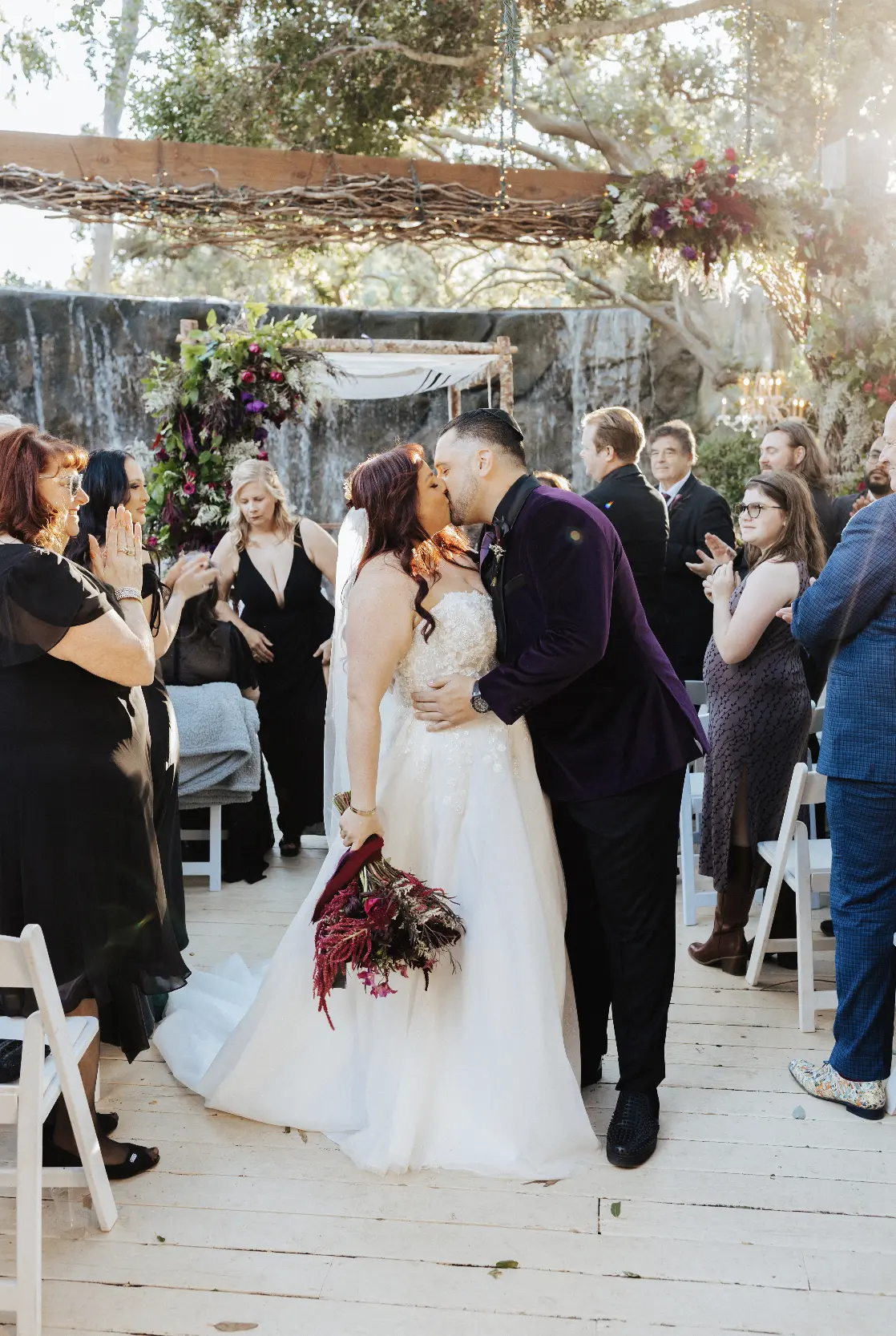 Bride Wearing A-line Bridal Dress Ainsleigh By Rebecca Ingram Kissing Groom With Family Cheering