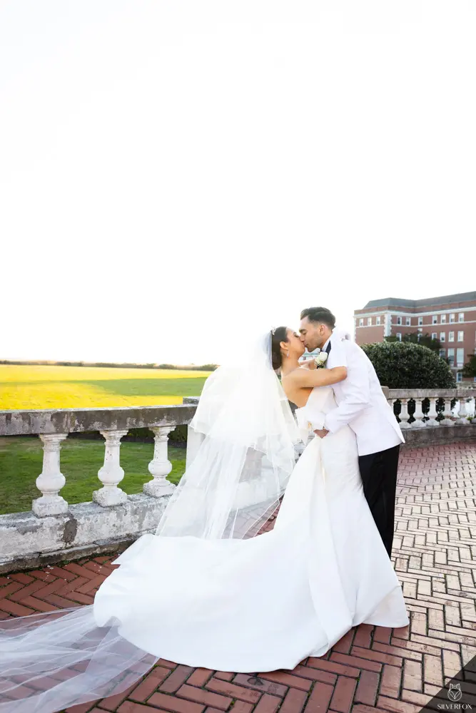 Bride And Groom Sharing Kiss. Bride Wearing Unique Strapless Wedding Gown With Statement Bow Called Mitchell By Maggie Sottero