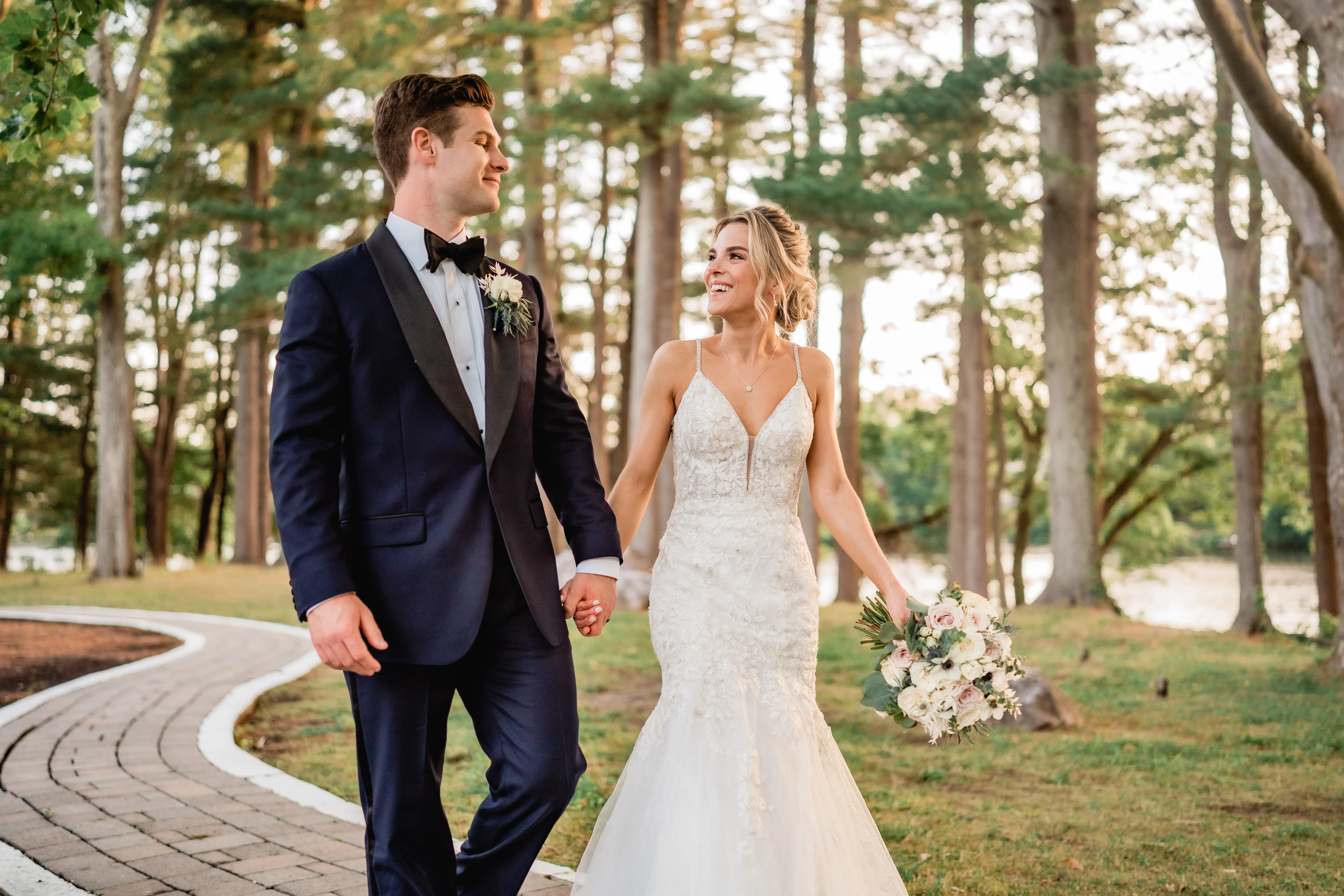 Bride smiling at her groom outside holding hands.