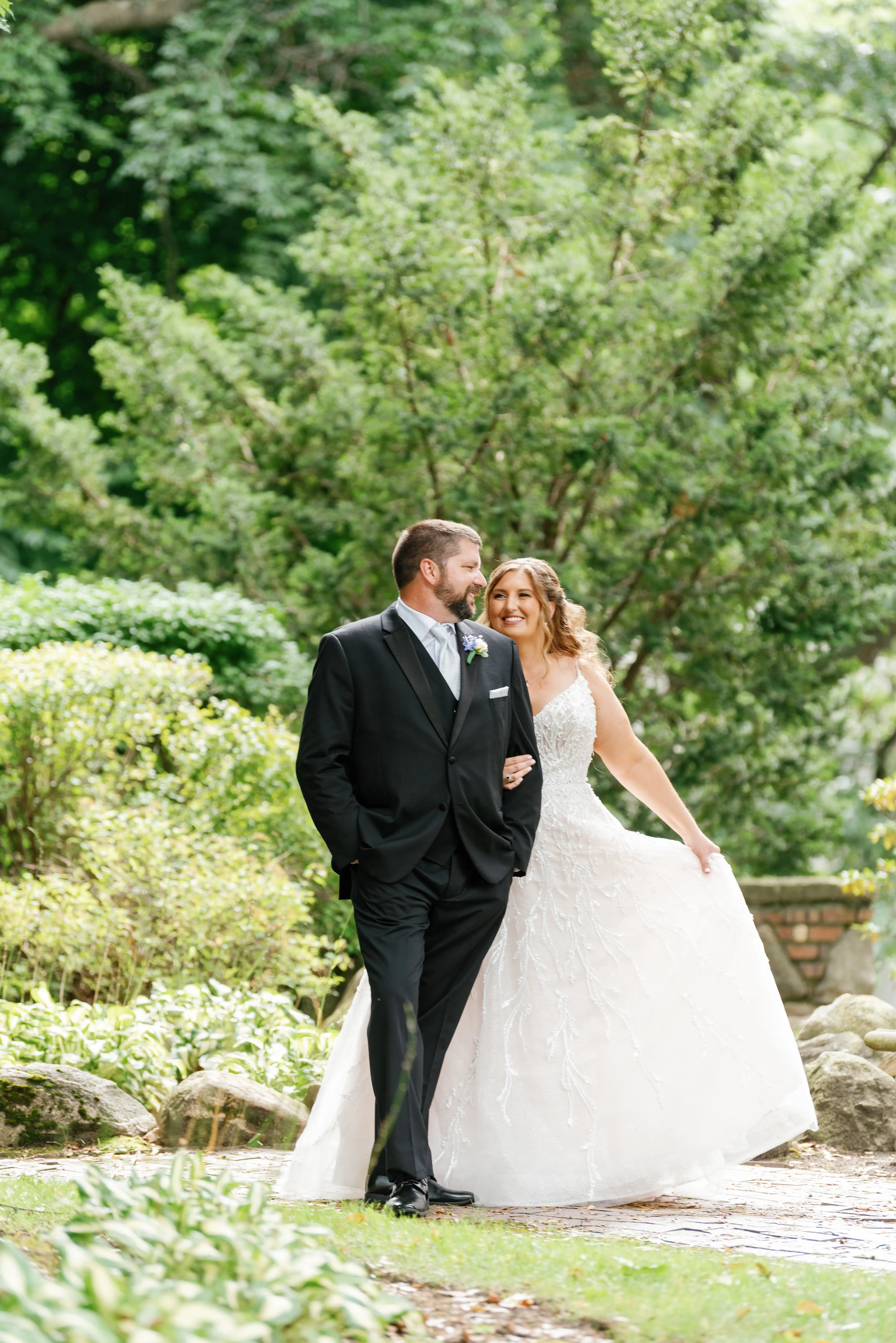 Bride Wearing Beaded Wedding Dress Called Marvine By Sottero And Midgley Walking With Groom In A Garden