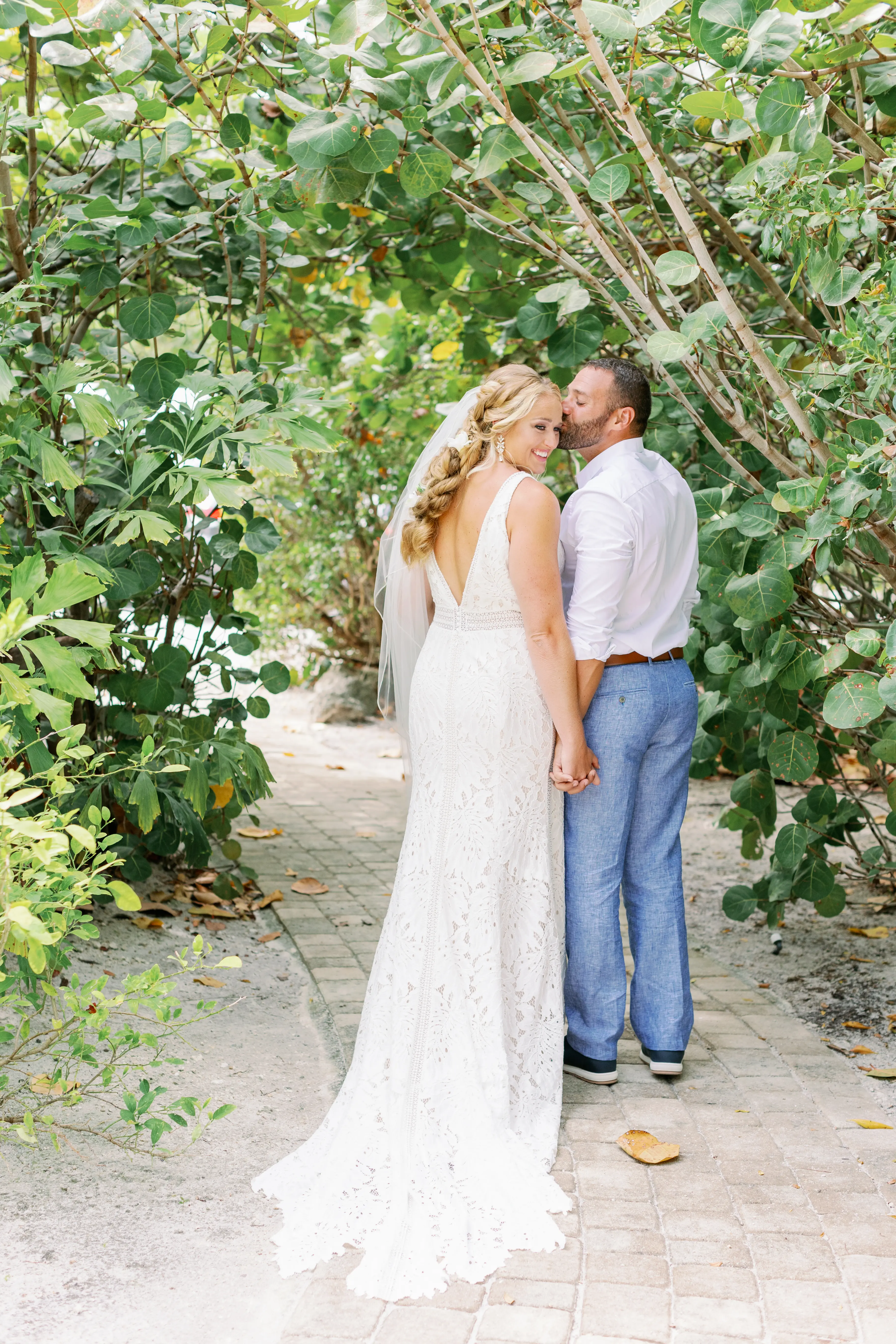 Groom kissing bride on her head.