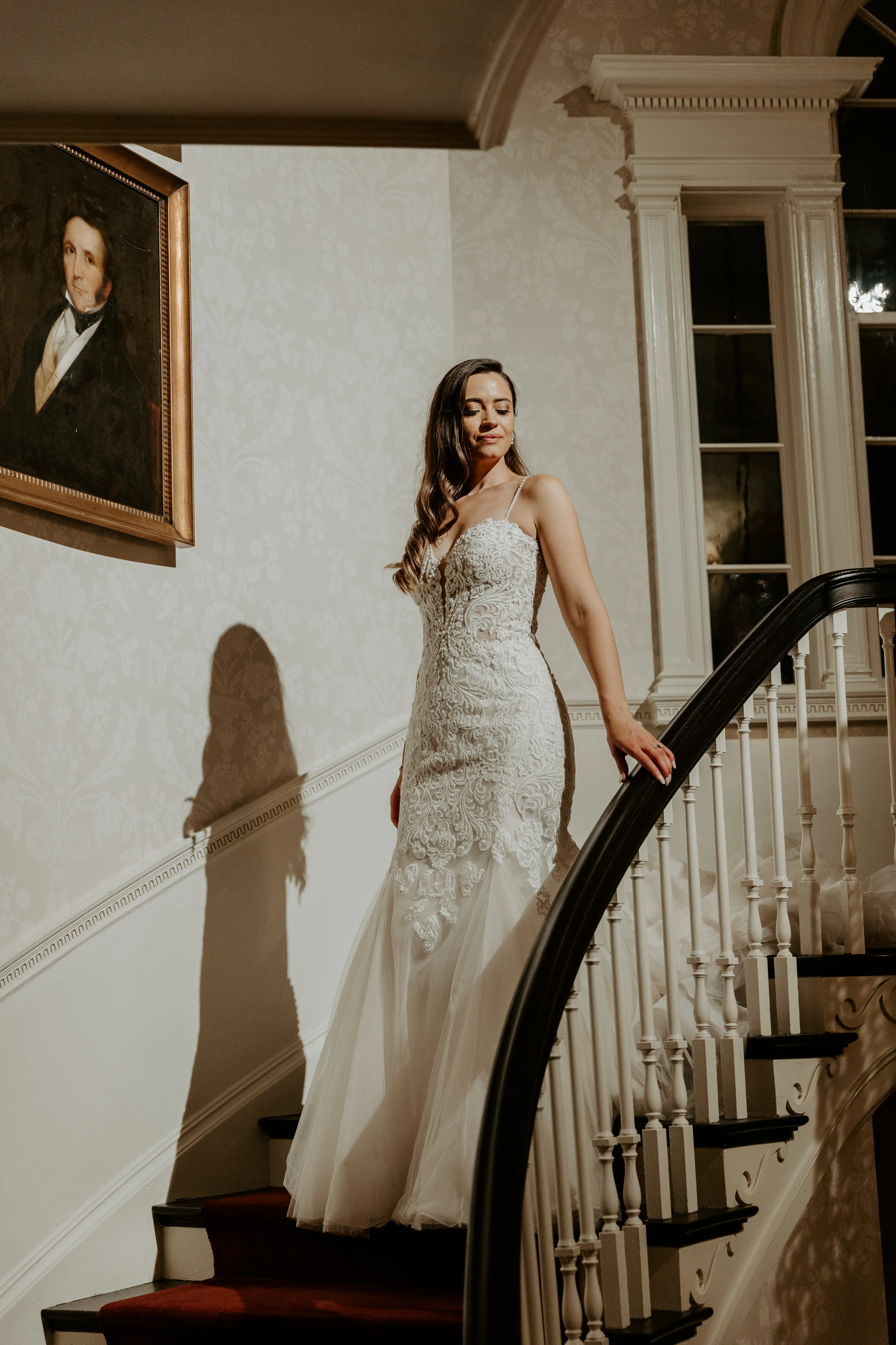 Bride wearing lace fit-and-flare wedding dress on staircase.