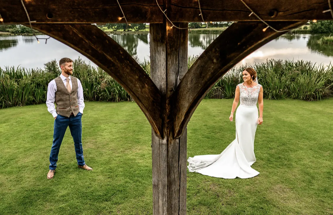 Bride and groom looking at each other under a bridge.