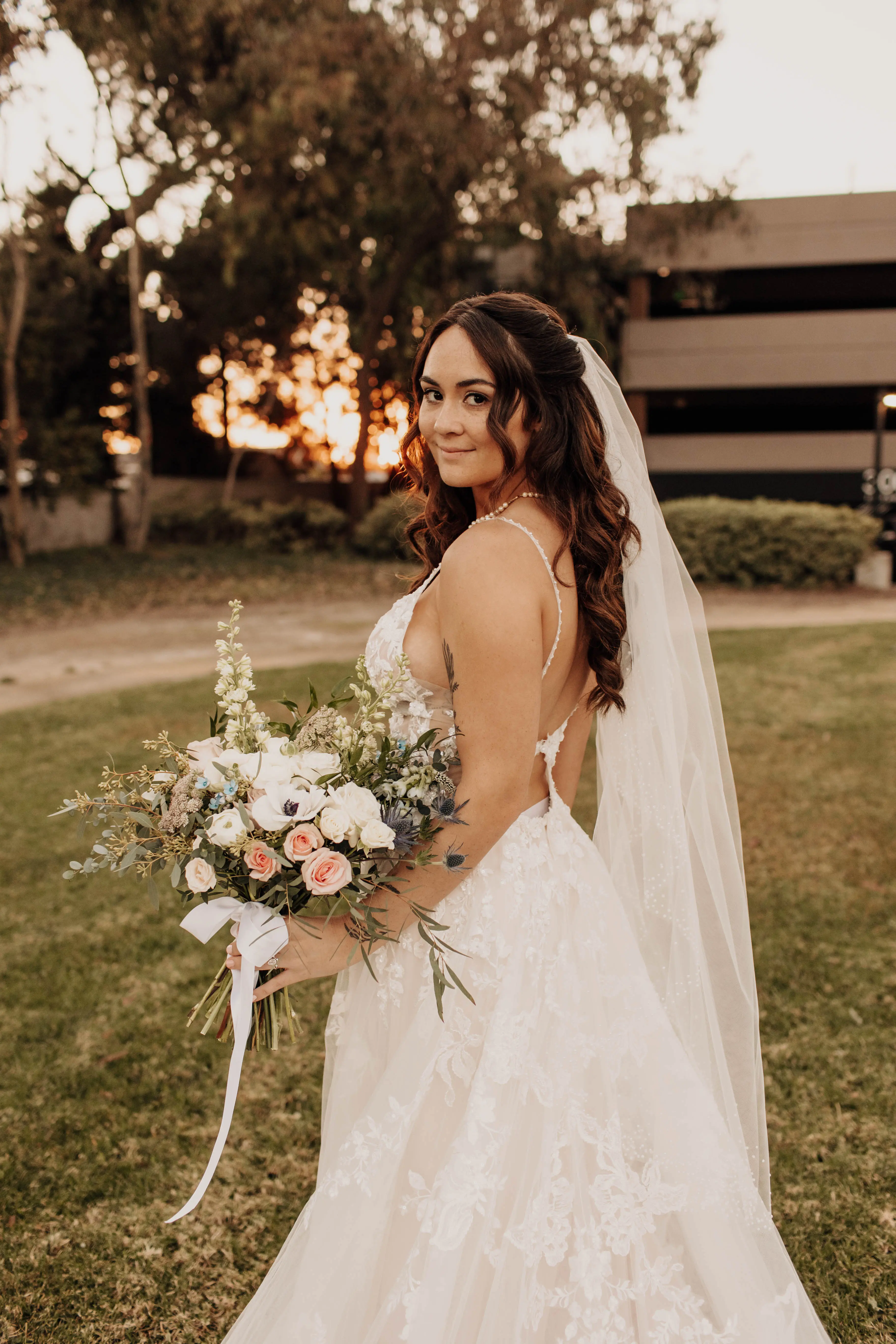 Bride wearing wedding dress called Marlow with keyhole back, holding pretty peach and ivory bouquet.
