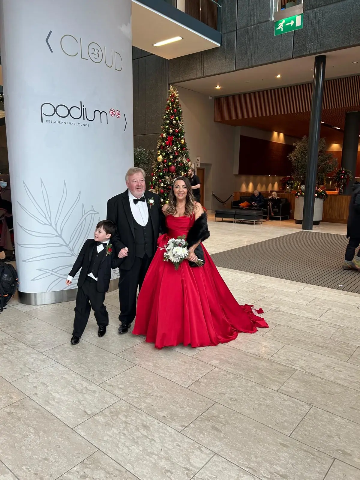 Bride Wearing Red Aline Wedding Dress Called Scarlet By Maggie Sottero Next To A Christmas Tree And Groom And Child