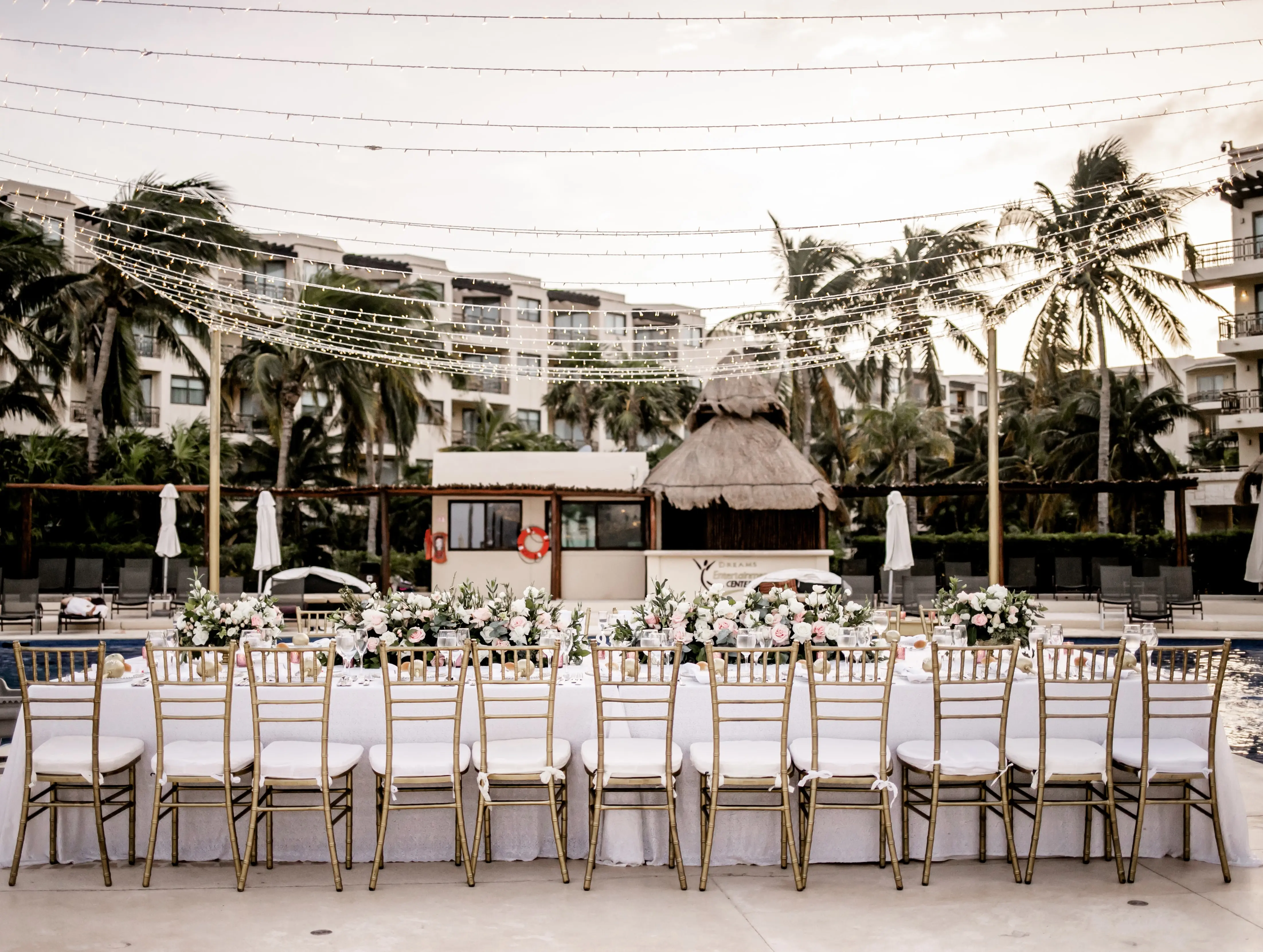 Table at wedding reception with fairy lights strung above.