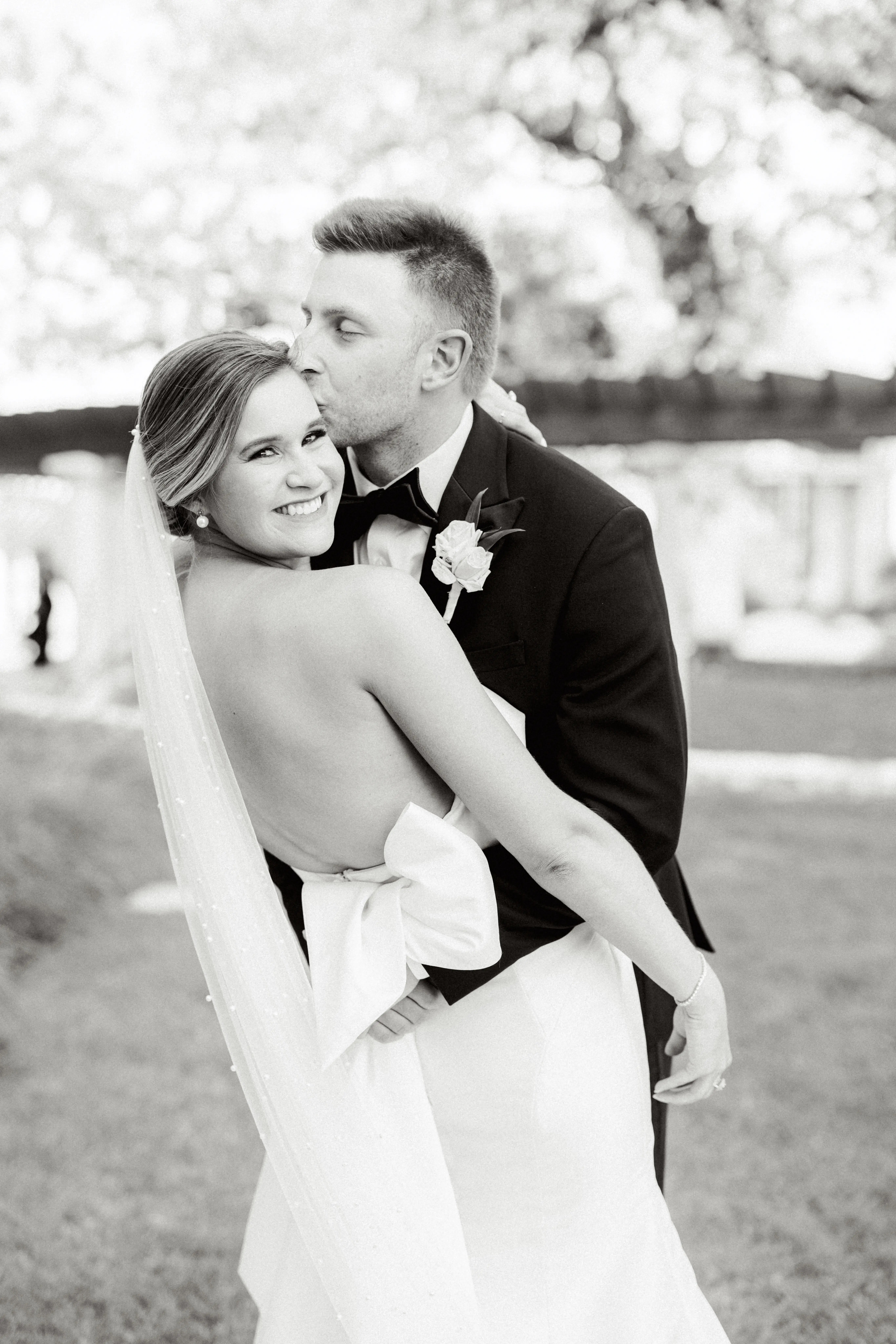 Groom With Bride Wearing Simple Sheath Wedding Dress With Bow Back Called Mitchell By Maggie Sottero