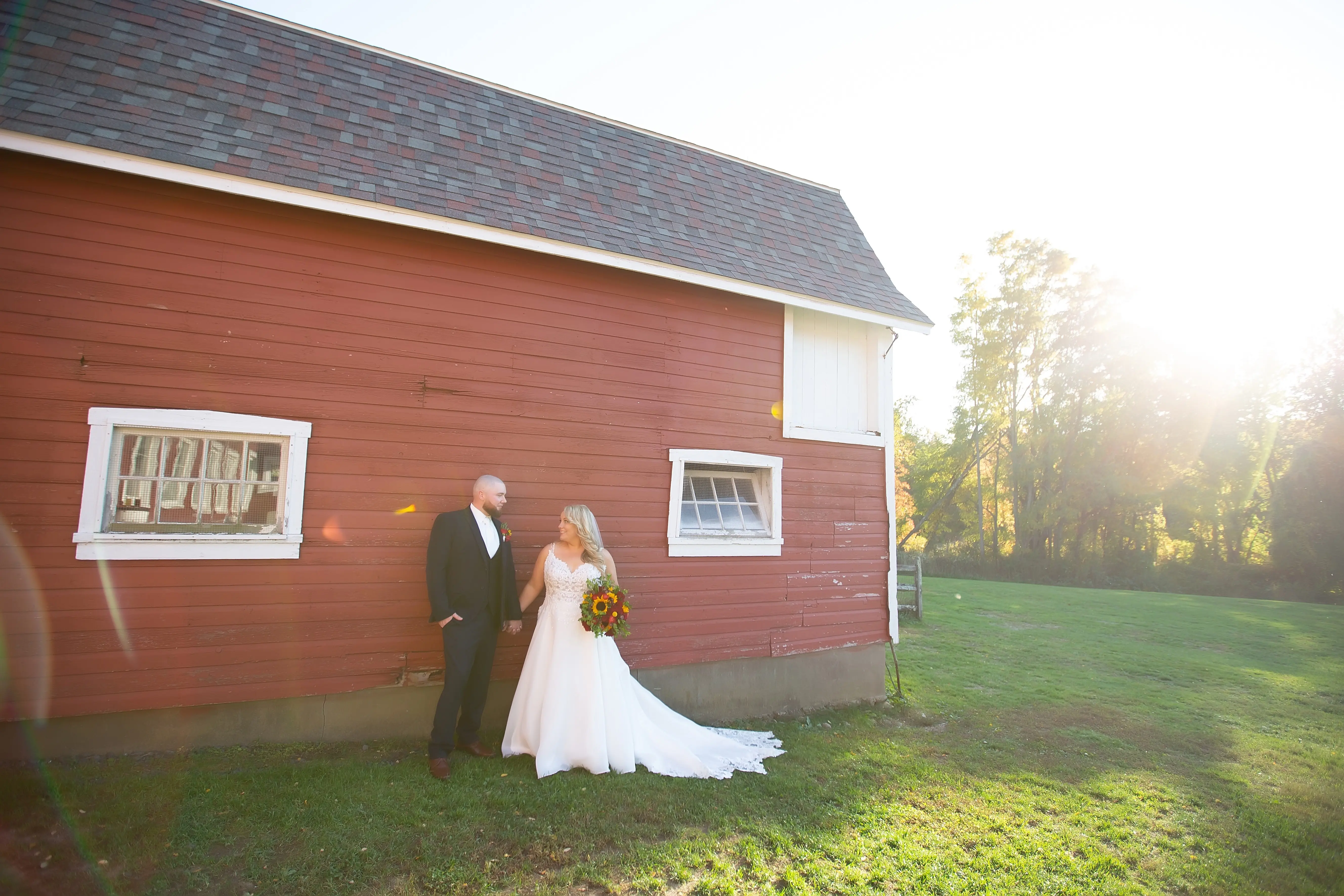 Groom with Bride in Front of Barn Wearing Wedding Dress Called Savannah by Maggie Sottero.