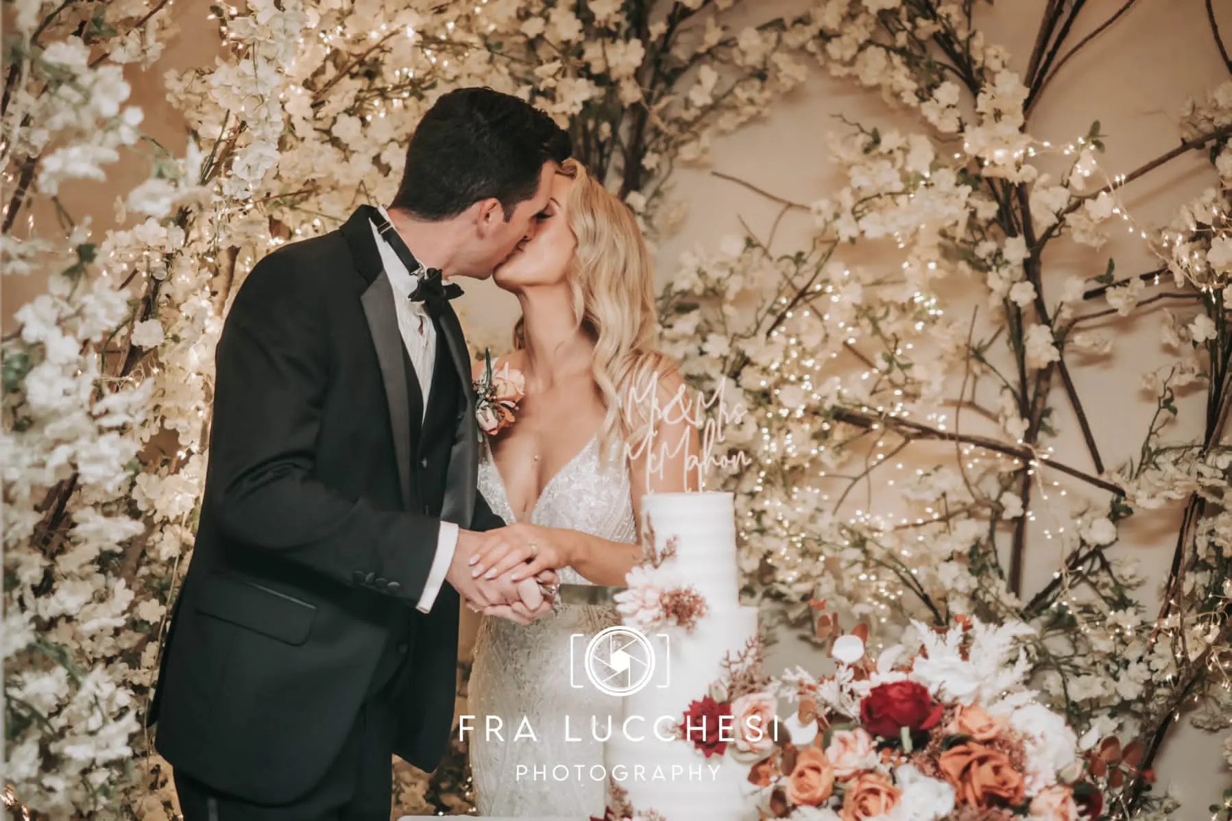 Bride wearing Bailey wedding dress by Sottero and Midgley cutting the cake with her husband