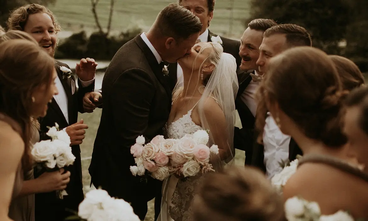 Bride wearing Lace Fit-and-Flare Wedding Dress called Tuscany Lynette by Maggie Sottero kissing the groom