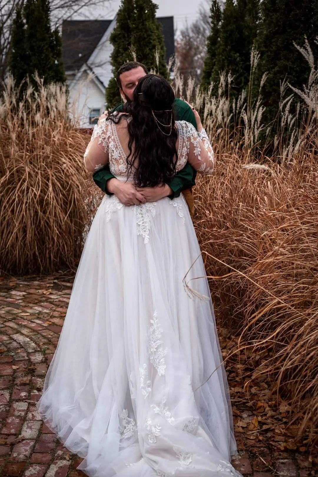 Bride and groom kissing in tall grass.