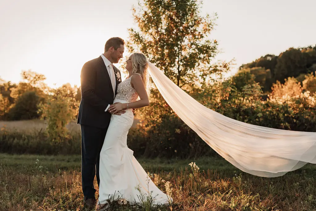 Bride and groom holding each other closely at sunset.