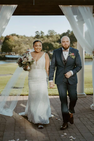 Bride with groom wearing art deco-inspired beaded wedding dress at outdoor venue.