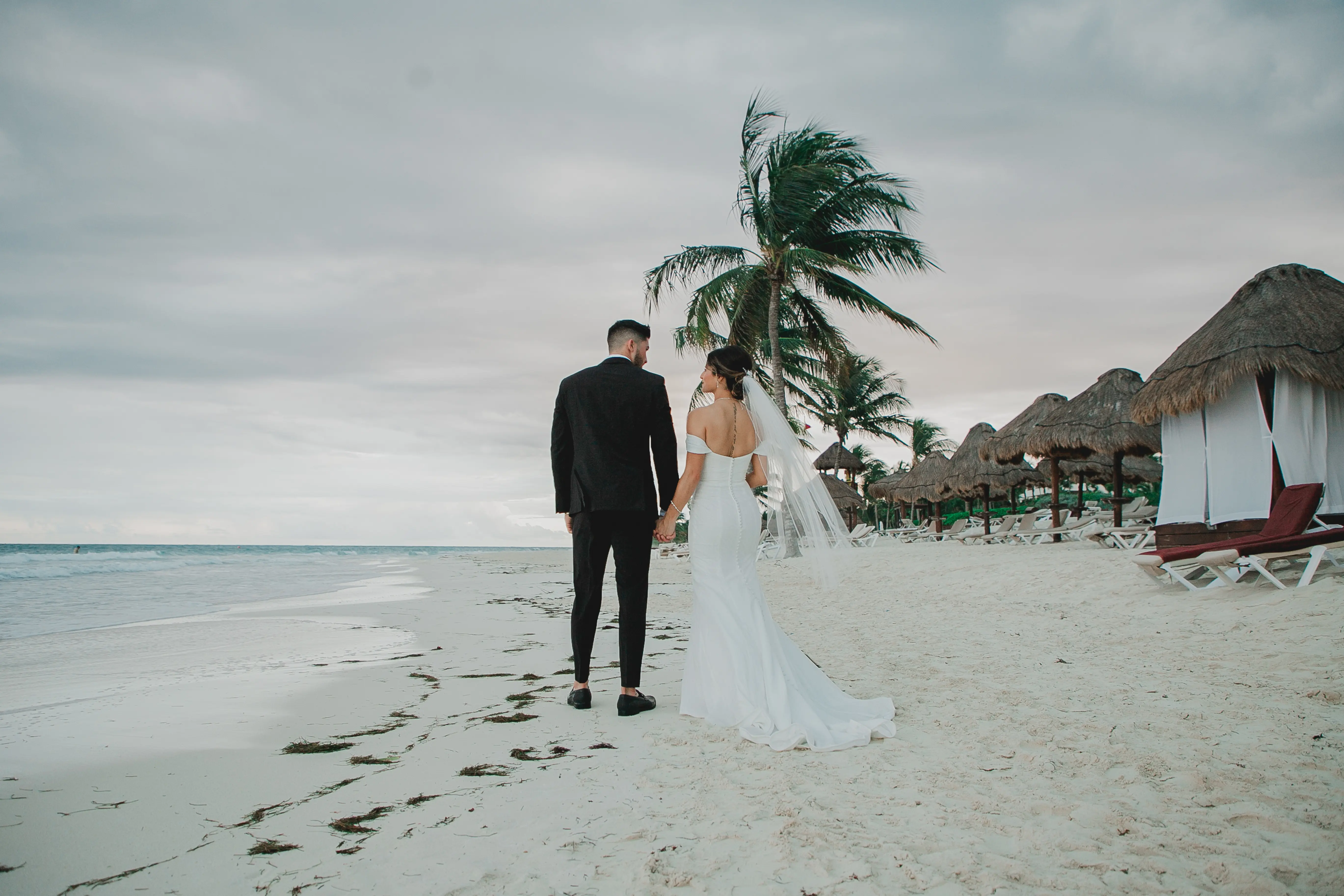 Bride Wearing Sparkly Fit And Flare Wedding Dress Called Anniston Lane By Maggie Sottero Walking With Groom On The Beach