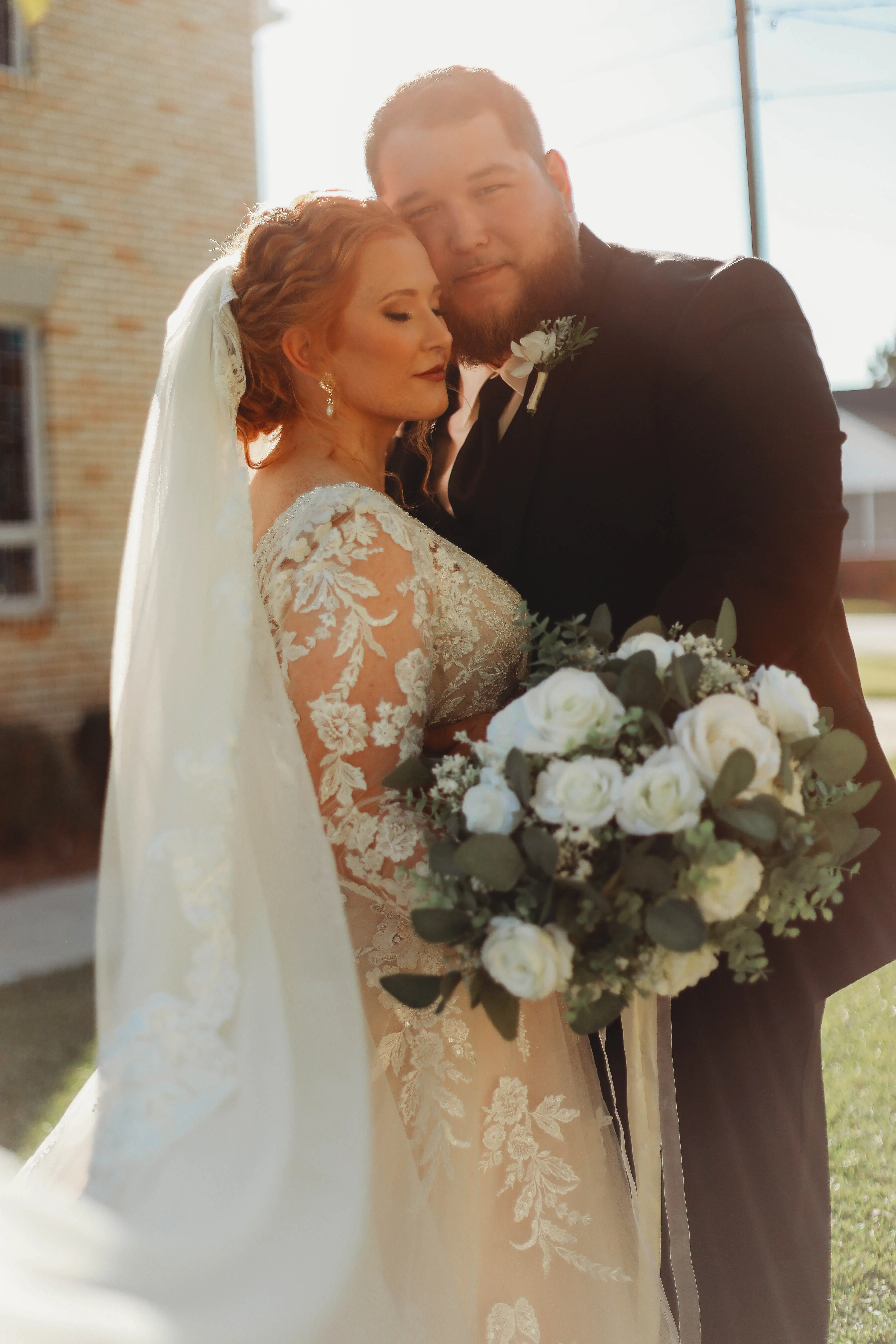 Bride Wearing Lace Long-Sleeve Wedding Gown Called Raphael By Maggie Sottero Holding Groom