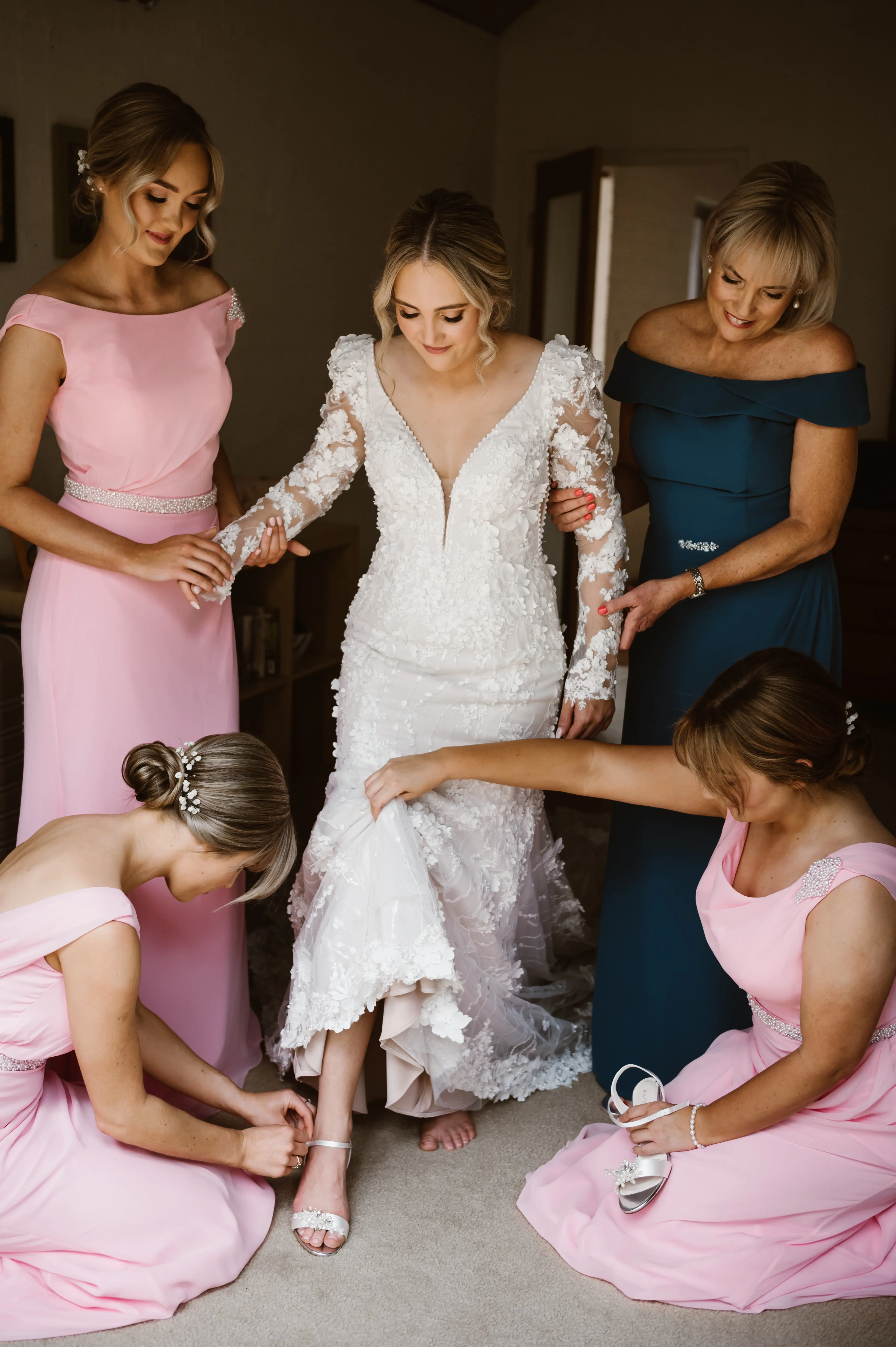 Bridal Party Helping Bride Get Ready. Bride in Vintage Inspired Puff Sleeve Mermaid Wedding Dress in 3-D Floral Motifs Called Cruz by Sottero & Midgley