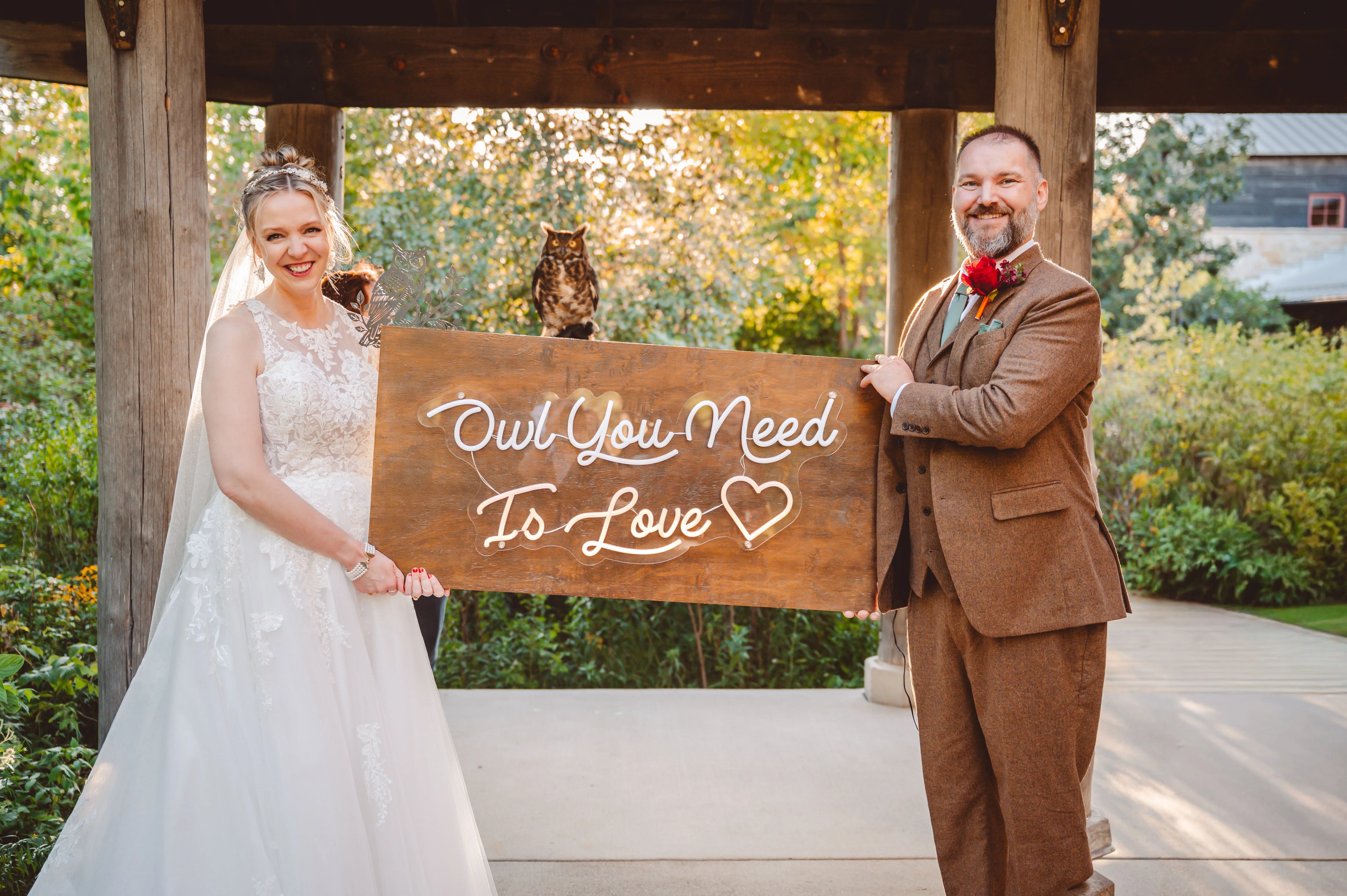 Bride wearing Lace Aline Wedding Dress Called Rickie By Rebecca Ingram With Groom Holding A Sign That Says Owl You Need Is Love