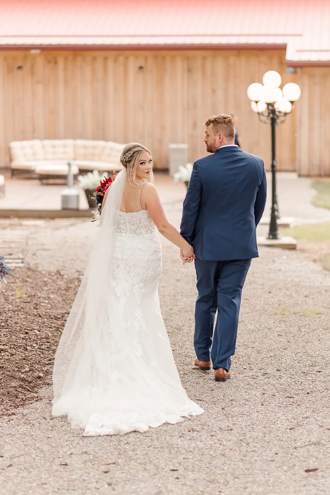 Bride Wearing Sexy Mermaid Lace Wedding Dress Called Fiona By Maggie Sottero Looking Back Holding Hands With Groom