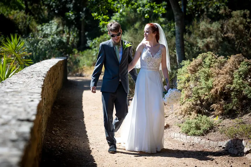 Bride Wearing Affordable Sheath Wedding Dress Called Lorraine By Rebecca Ingram Walking With Groom