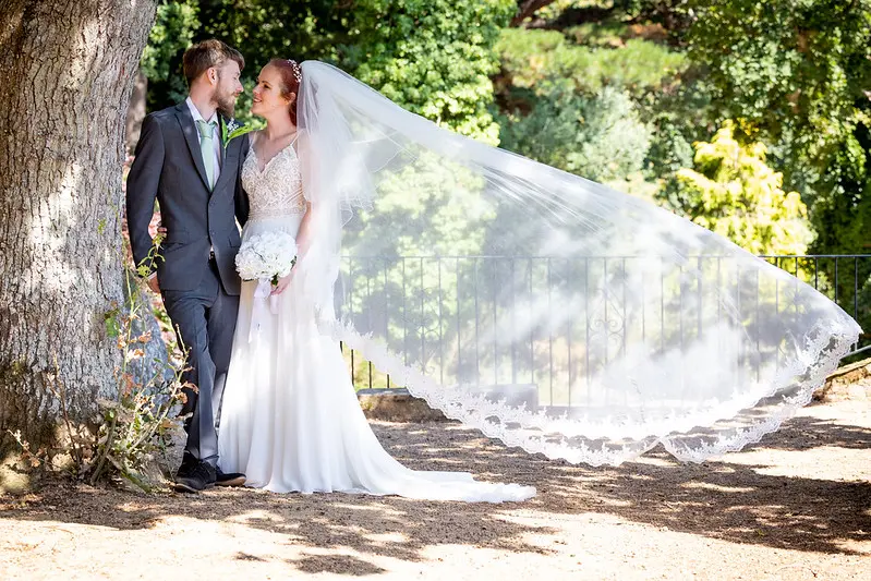 Bride Wearing Affordable Sheath Wedding Dress Called Lorraine By Rebecca Ingram With A Billowing Veil