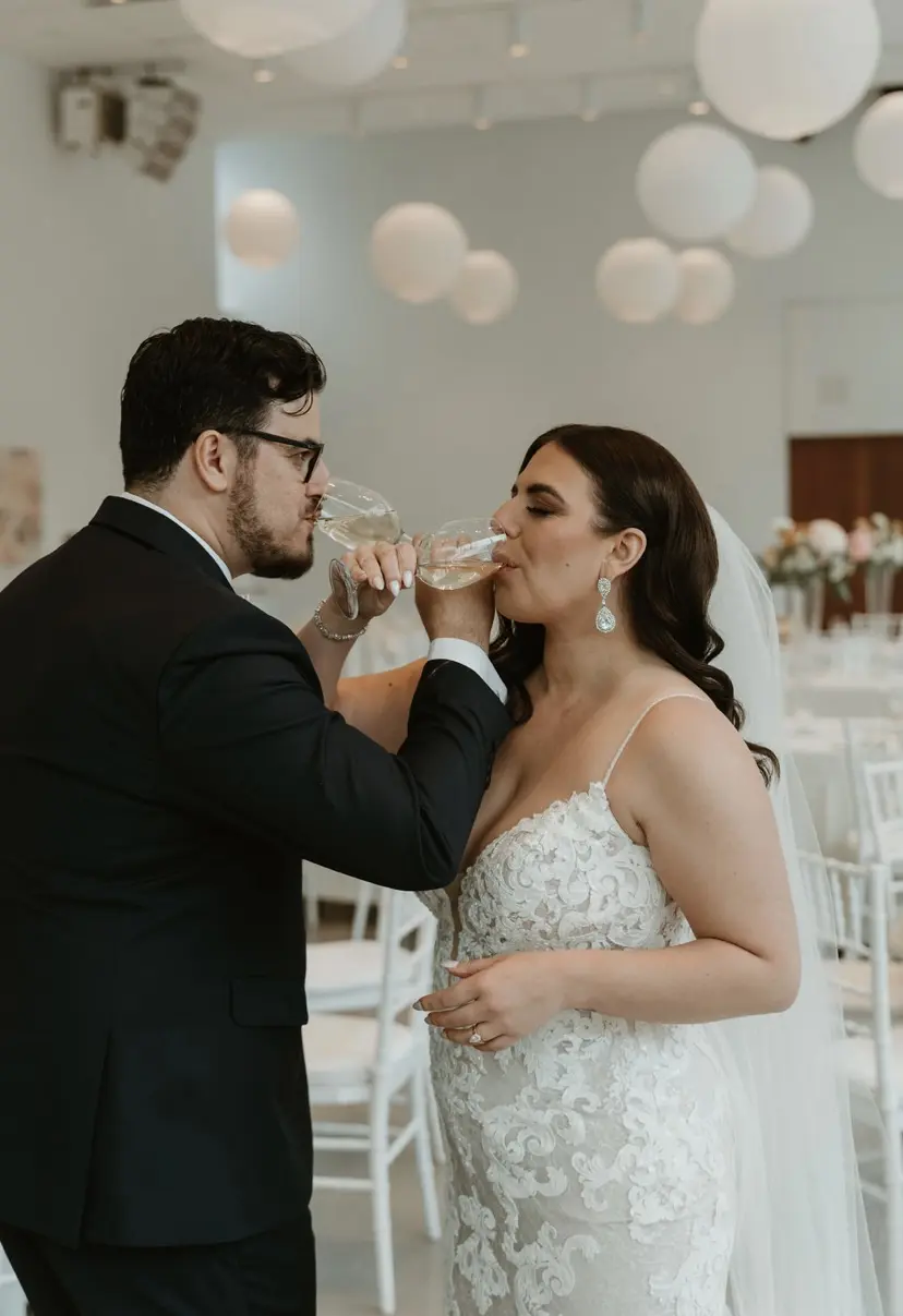 Bride wearing Tuscany Lynette wedding dress by Maggie Sottero drinking with her husband