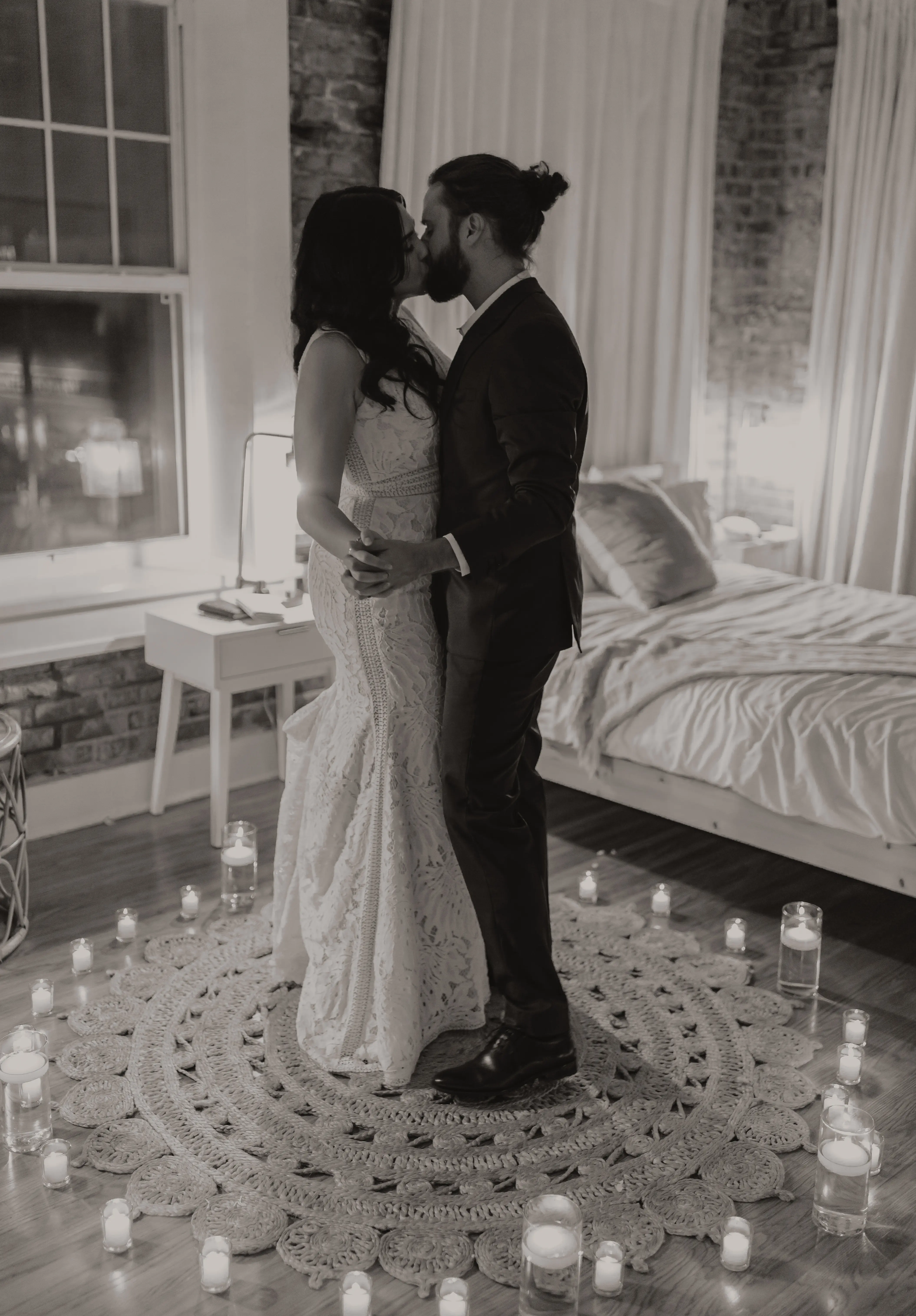 Newlyweds kissing in a circle of lit candles.