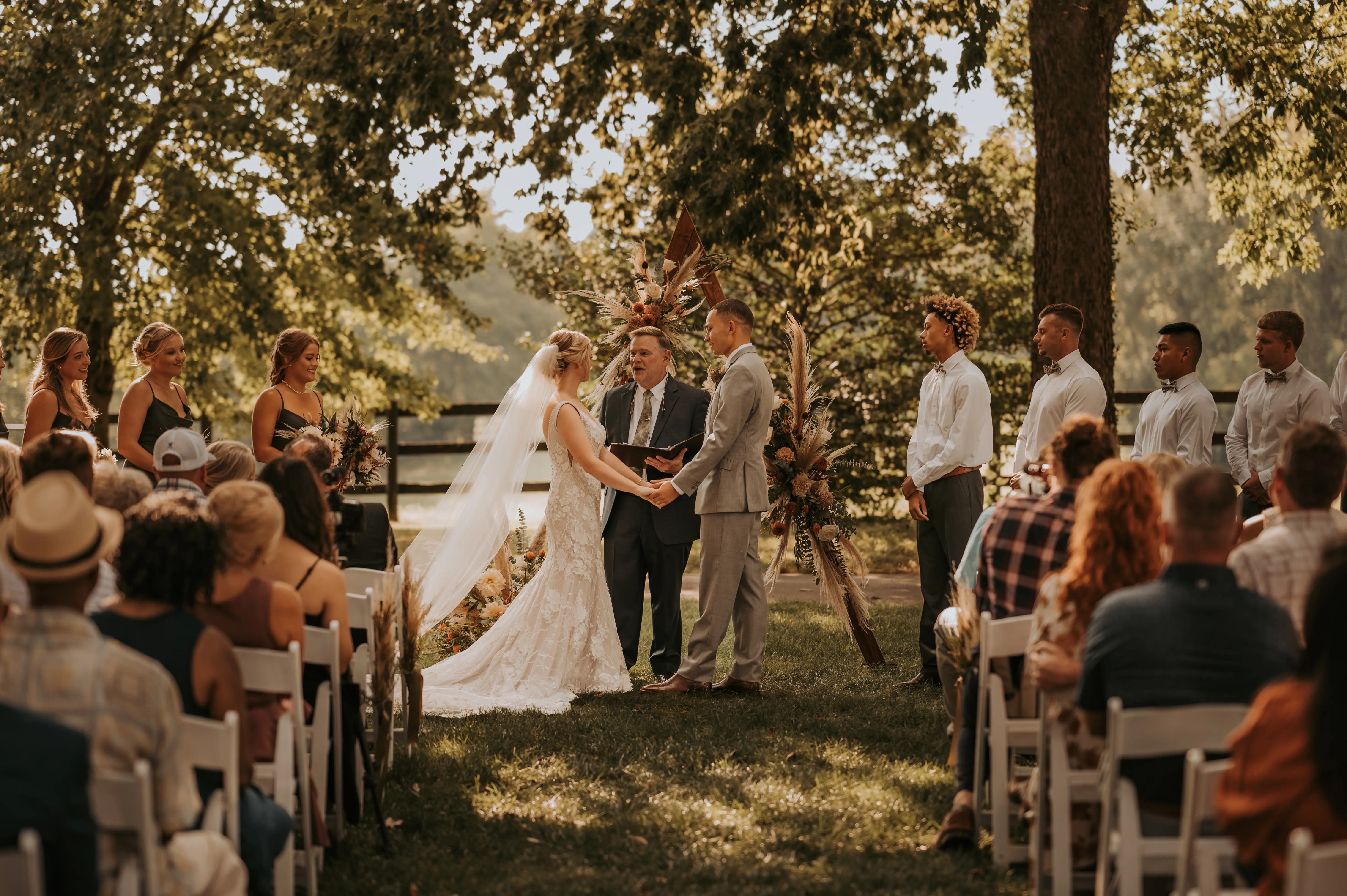 Groom at Altar Holding Hands with Bride in Mermaid Wedding Dress with 3-D Floral Motifs and Extended Scalloped Lace Train Called Cruz by Sottero & Midgley