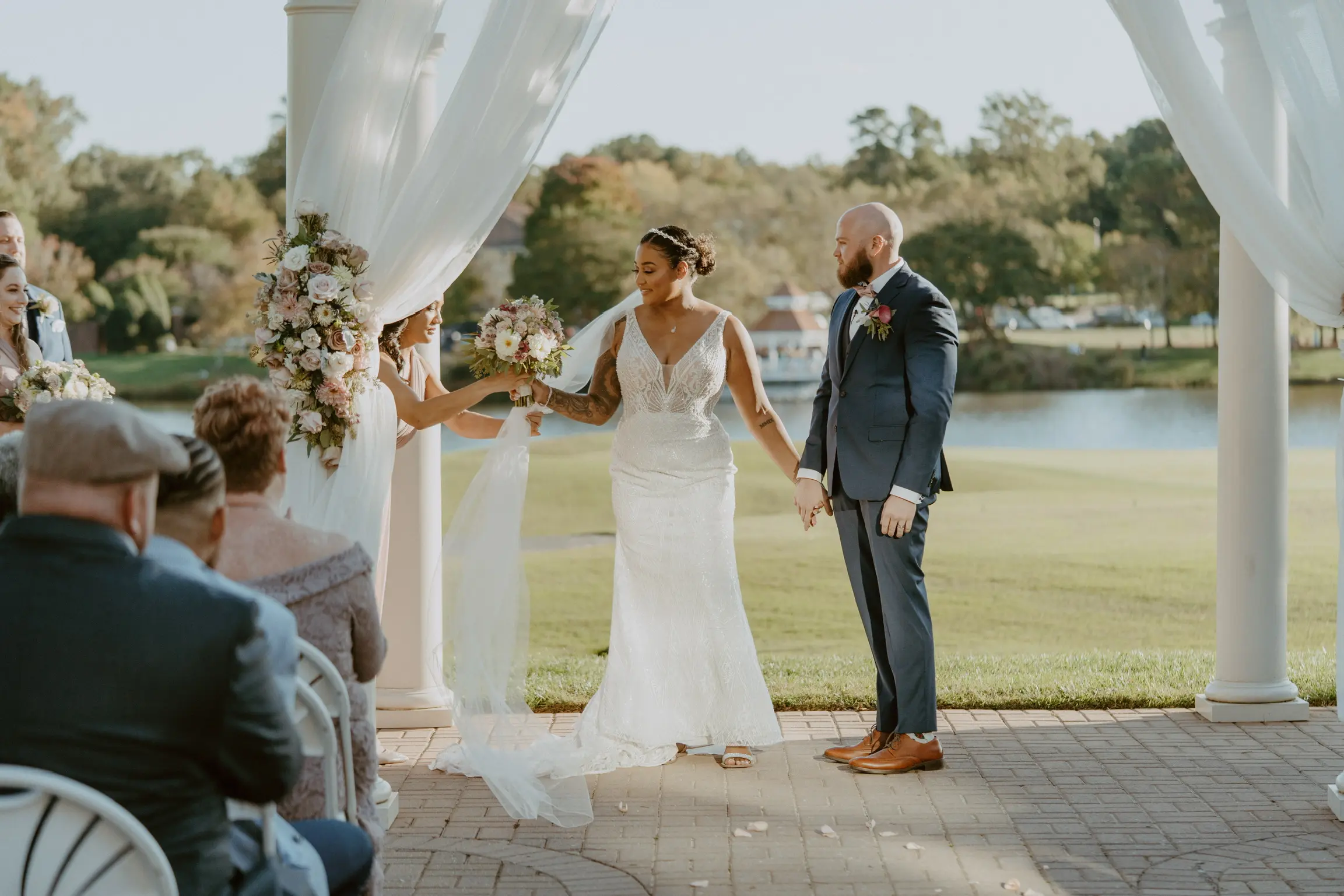 Bride with groom wearing art deco-inspired beaded wedding dress at outdoor venue.