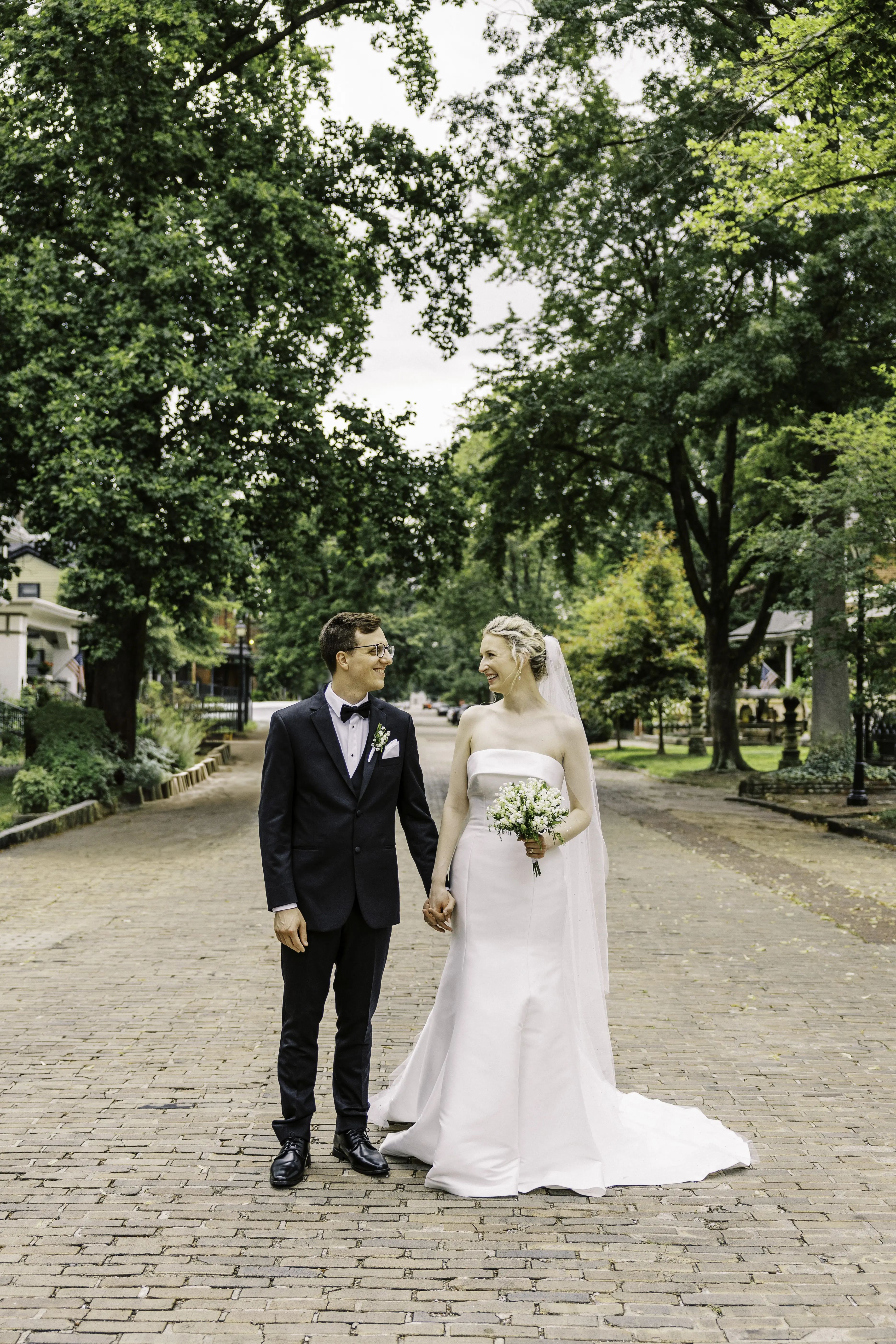 Bride wearing Mitchell Marie Vida by Maggie Sottero holding hands with her husband