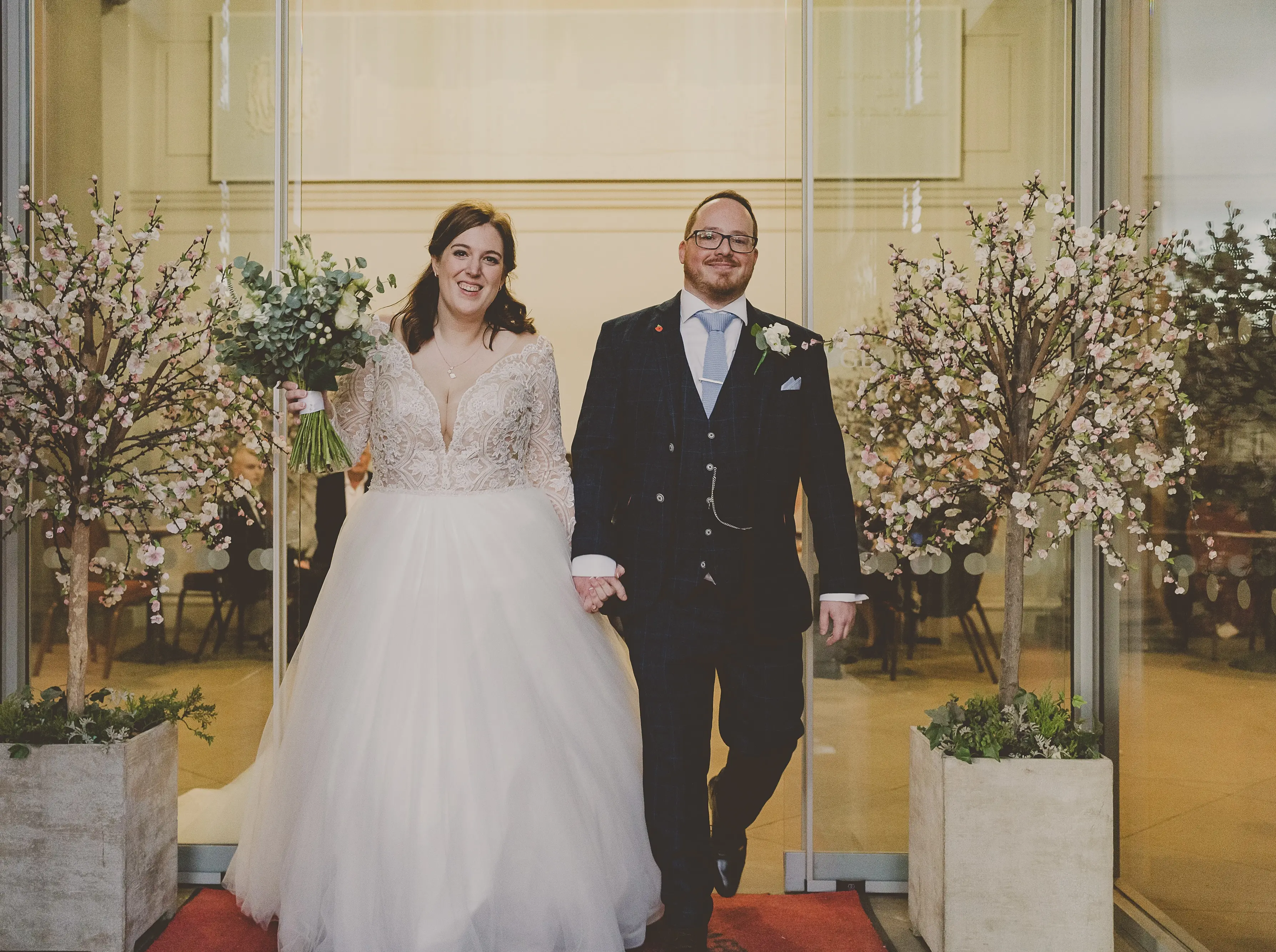 Bride And Groom Walking. Bride Wearing Lace Long Sleeve Ball Gown Wedding Dress With Tulle Skirt Called Mallory Dawn By Maggie Sottero