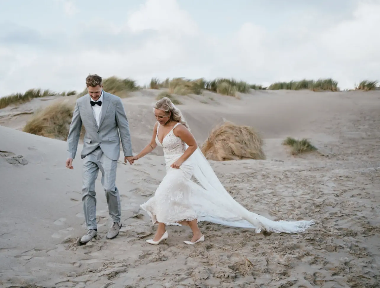 Bride Wearing Lace Fit-And-Flare Wedding Dress Called Hamilton By Sottero And Midgley Walking On The Beach With Groom