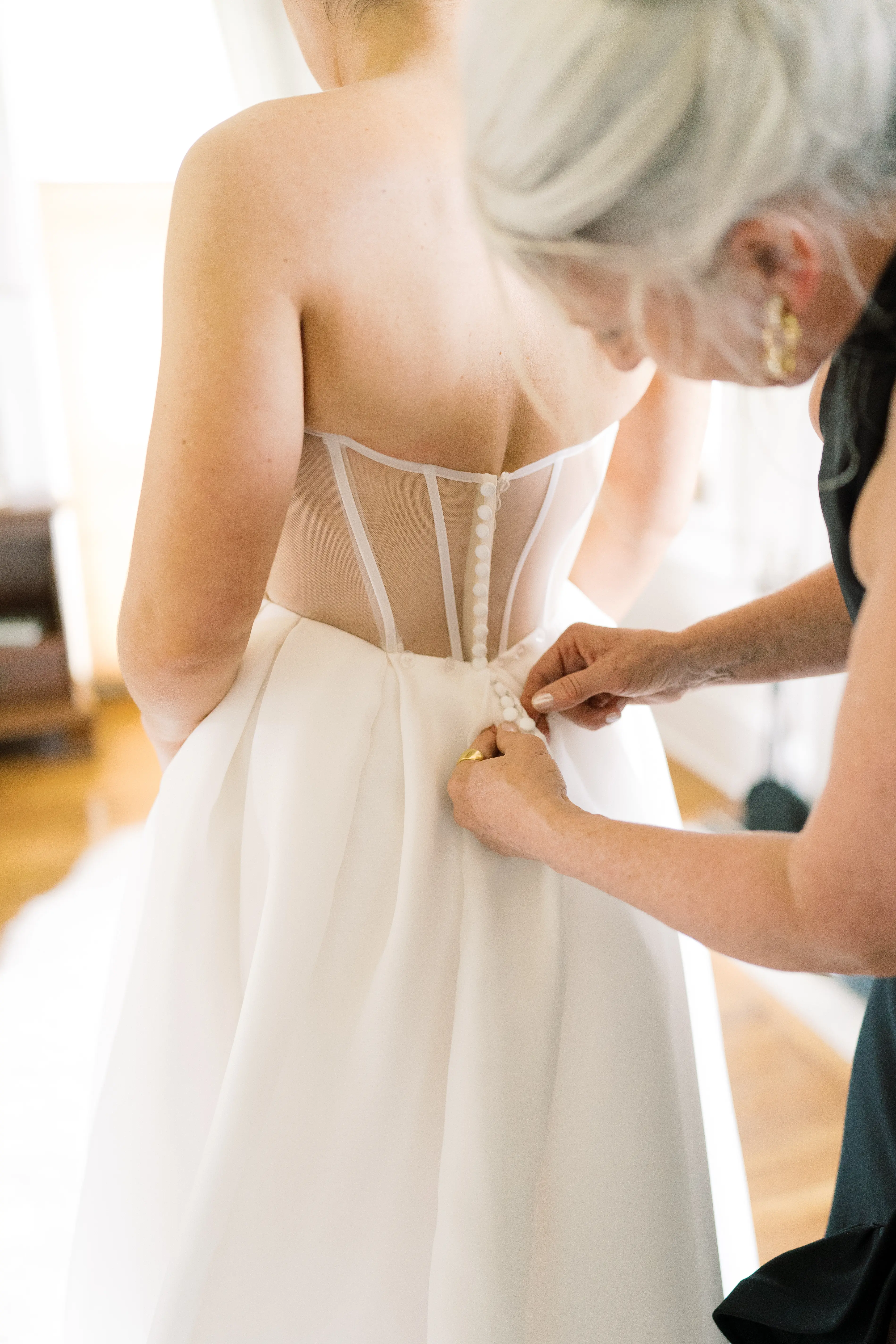 Bride wearing Nisha by Maggie Sottero being buttoned up