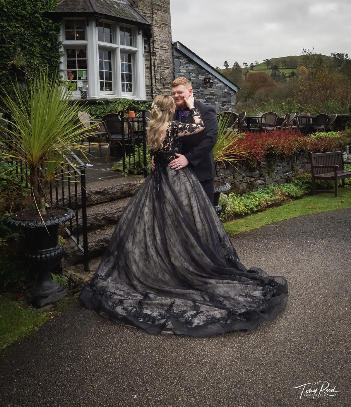 Groom with Bride In A Black Floral Long Sleeve Ball Gown Wedding Dress Named Zander By Sottero And Midgley