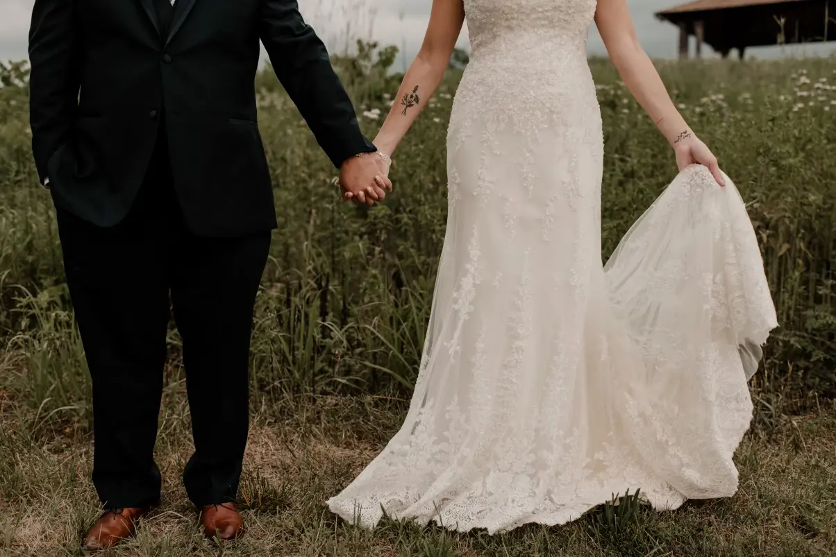 Bride and groom holding hands with just bottom half of couple visible.