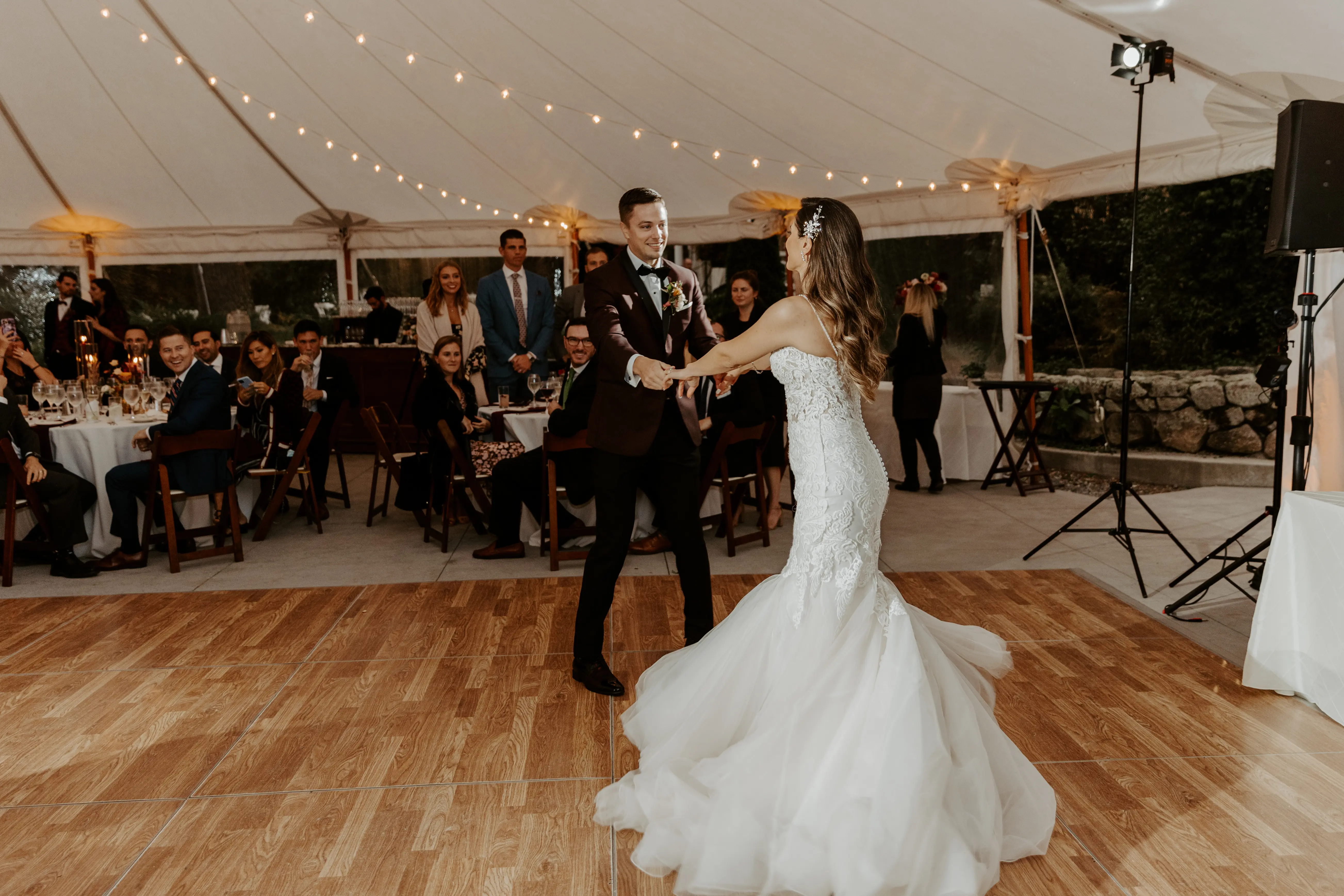 Bride with groom wearing lace fit-and-flare wedding dress dancing on dance floor outside.