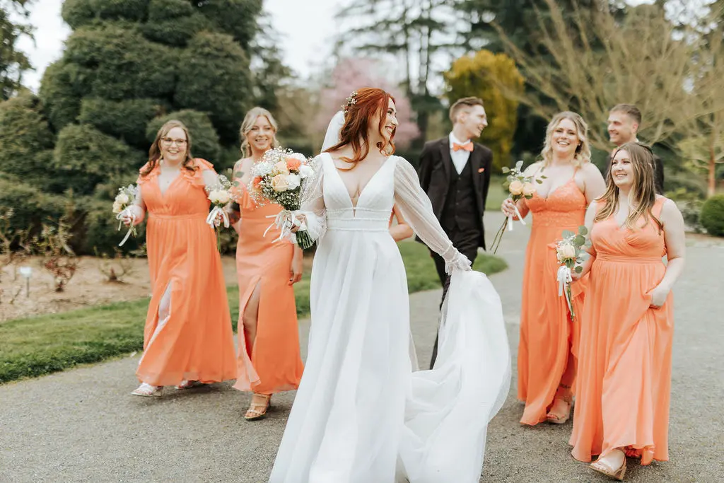 Bride Wearing Sexy Long Sleeve A-Line Wedding Dress Walking with Bridesmaids Outdoors.