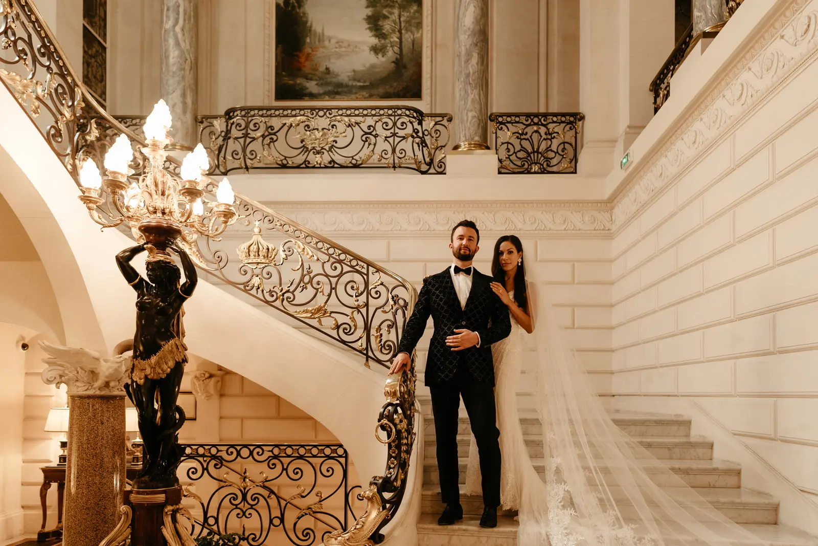 Groom Posing On Staircase With Bride In Beaded Lace Sheath Bridal Gown Called Barrett By Sottero And Midgley