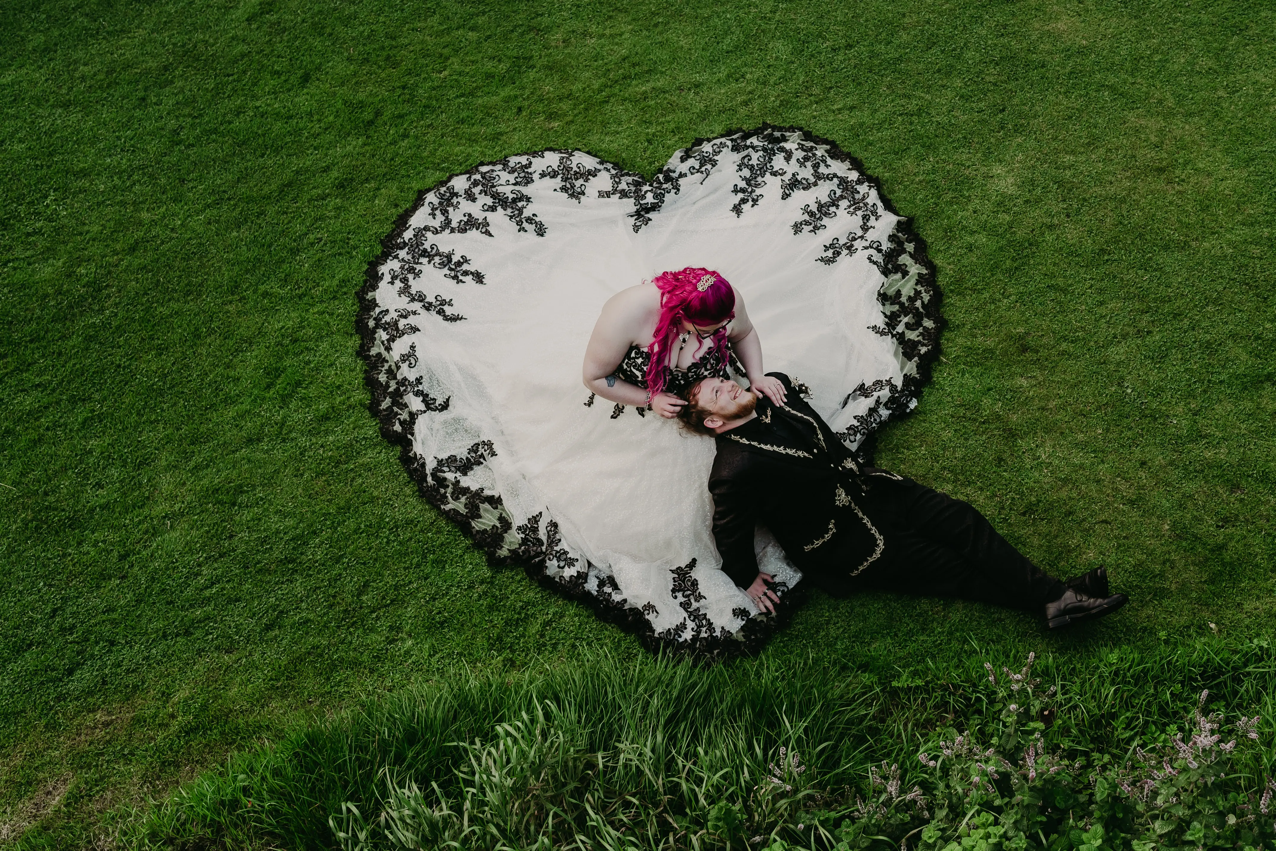 Bride Wearing Gothic Black Lace Wedding Dress Called Tristyn By Maggie Sottero With Dress Shaped As A Heart Holding Groom