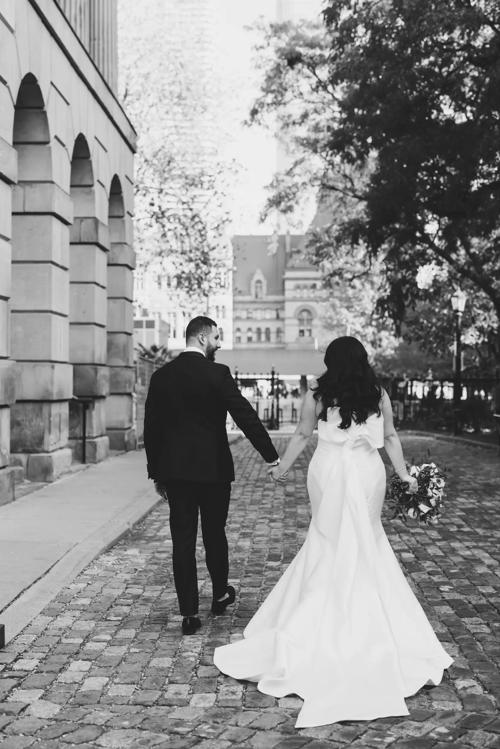 Bride with groom wearing strapless satin mermaid wedding dress with big bow on the back.