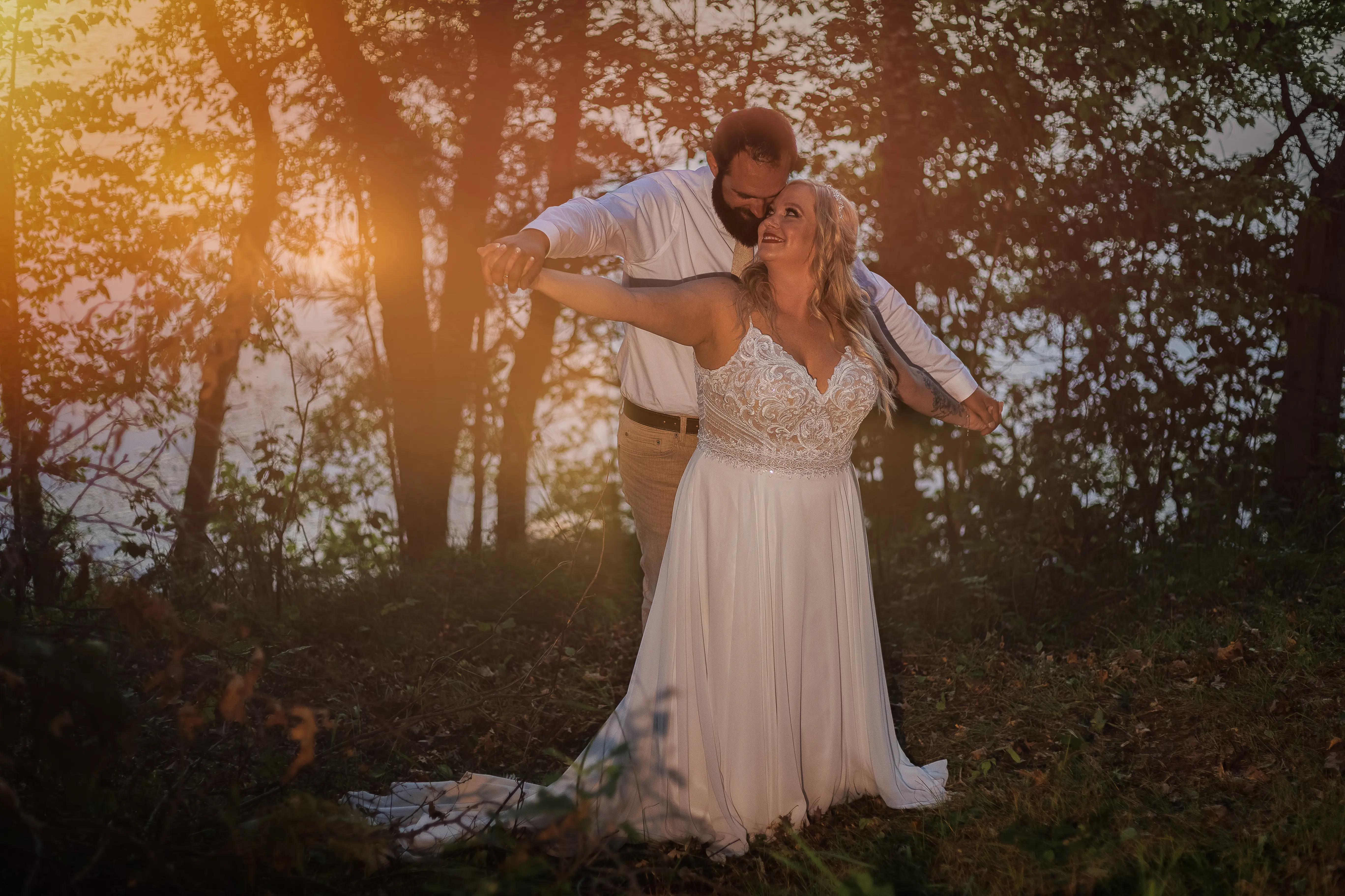 Bride Wearing Beaded Wedding Dress With Flowy Skirt Called Lorraine By Rebecca Ingram With Groom Behind Arms Spread Out