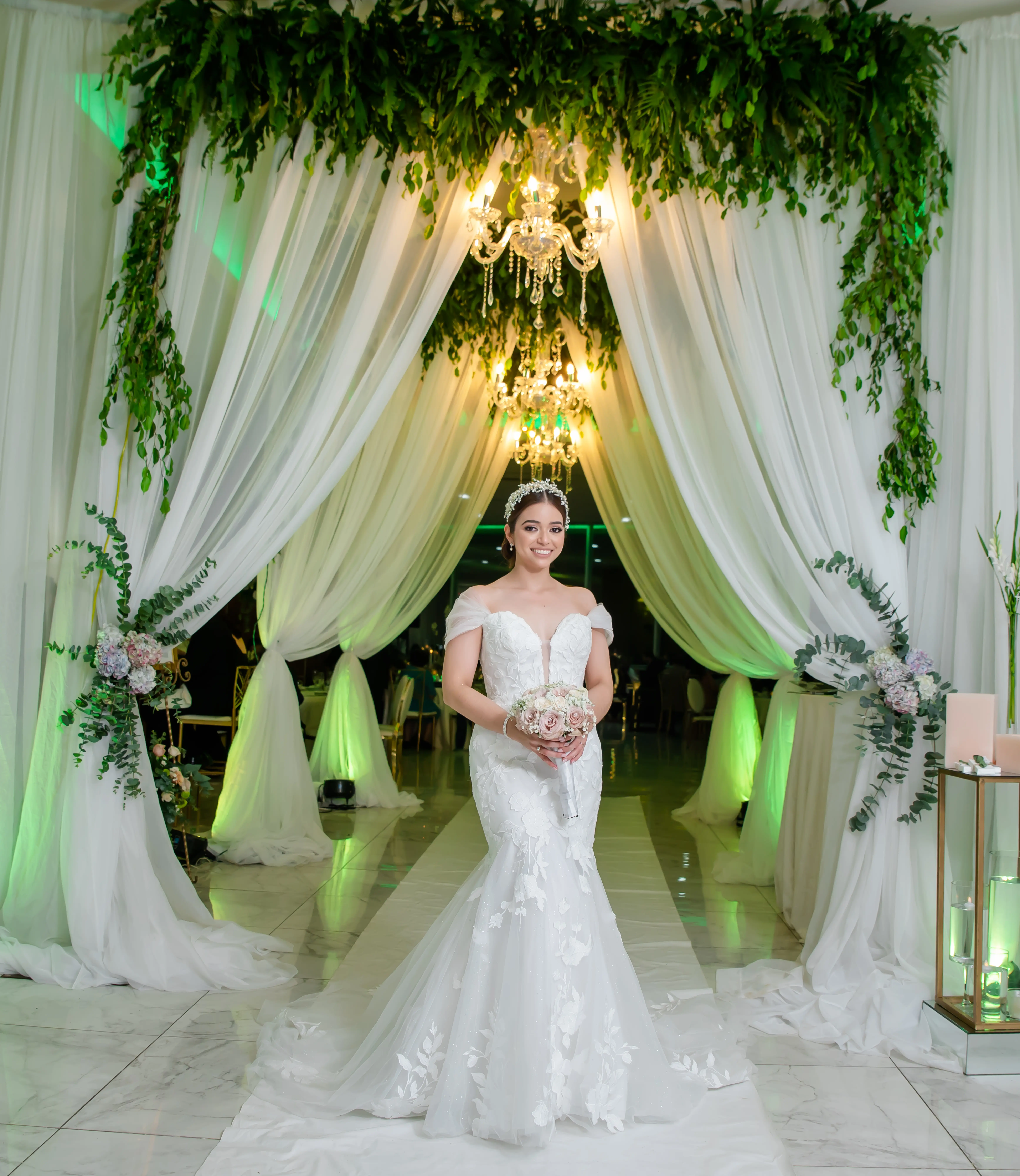Bride Holding Bouquet at Wedding with Greenery Background Wearing Wedding Gown Called Hattie by Rebecca Ingram