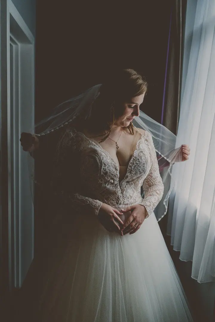 Bride Wearing Dreamy Long Sleeve Ballgown Wedding Dress Called Mallory Dawn By Maggie Sottero Putting On Veil