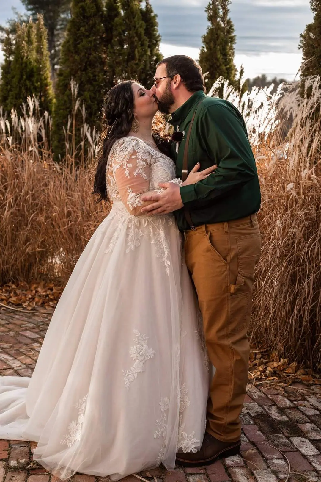 Bride and groom kissing in tall grass.