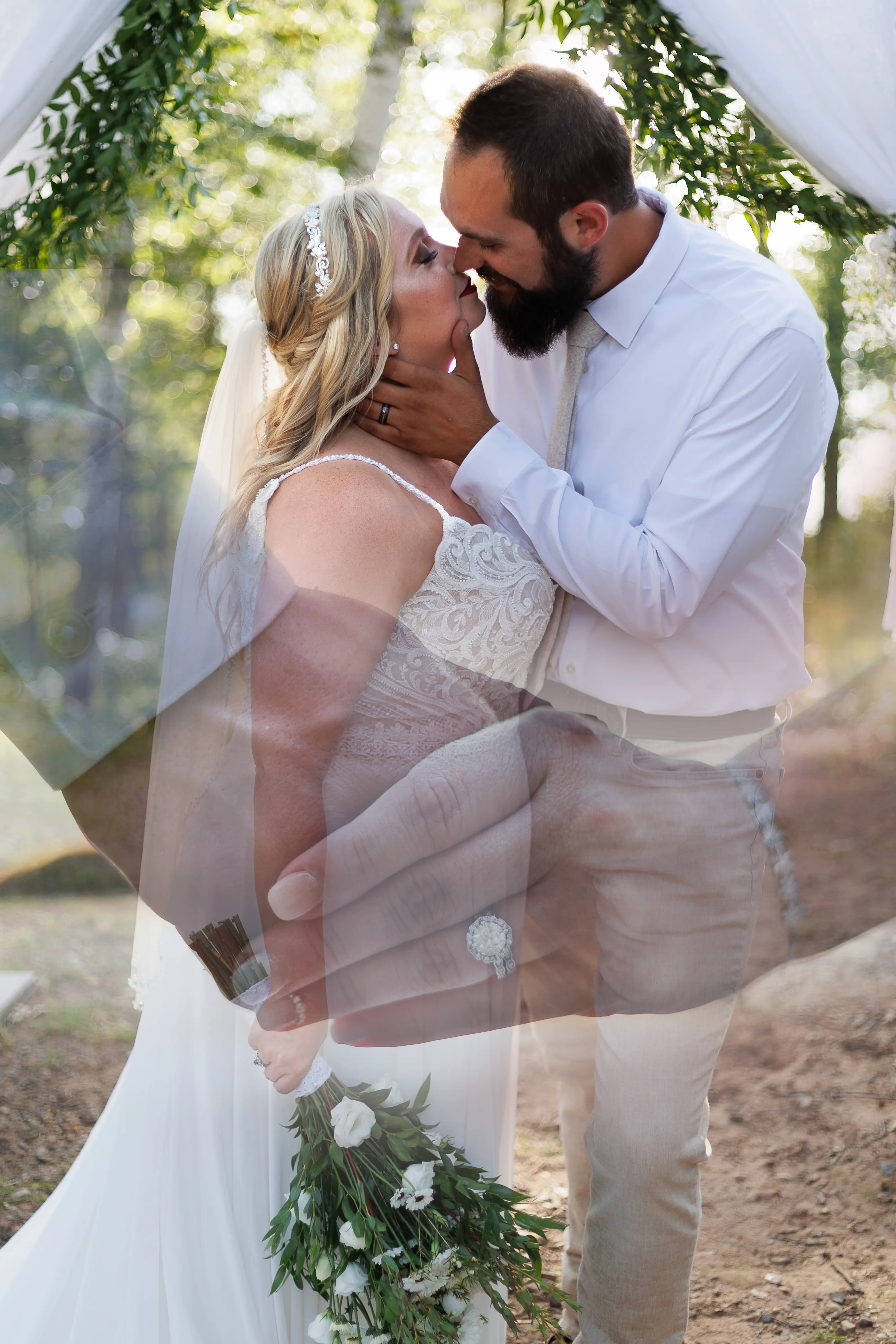 Bride Wearing Beaded Wedding Dress With Flowy Skirt Called Lorraine By Rebecca Ingram Kissing Groom With Hands Overlayed