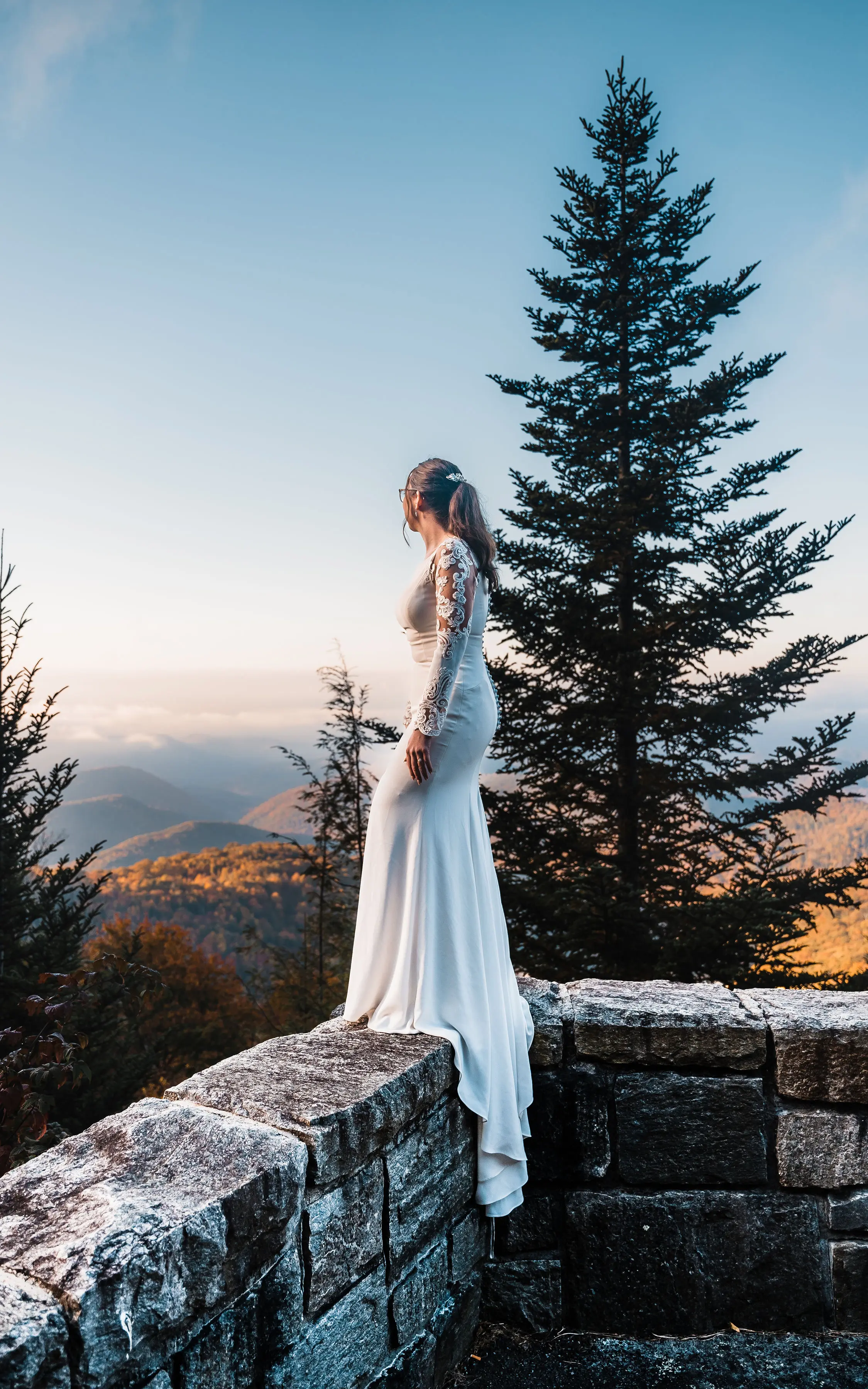 Bride Wearing Simple Long Sleeve Wedding Dress Called Bethany By Rebecca Ingram On A Stone Fence