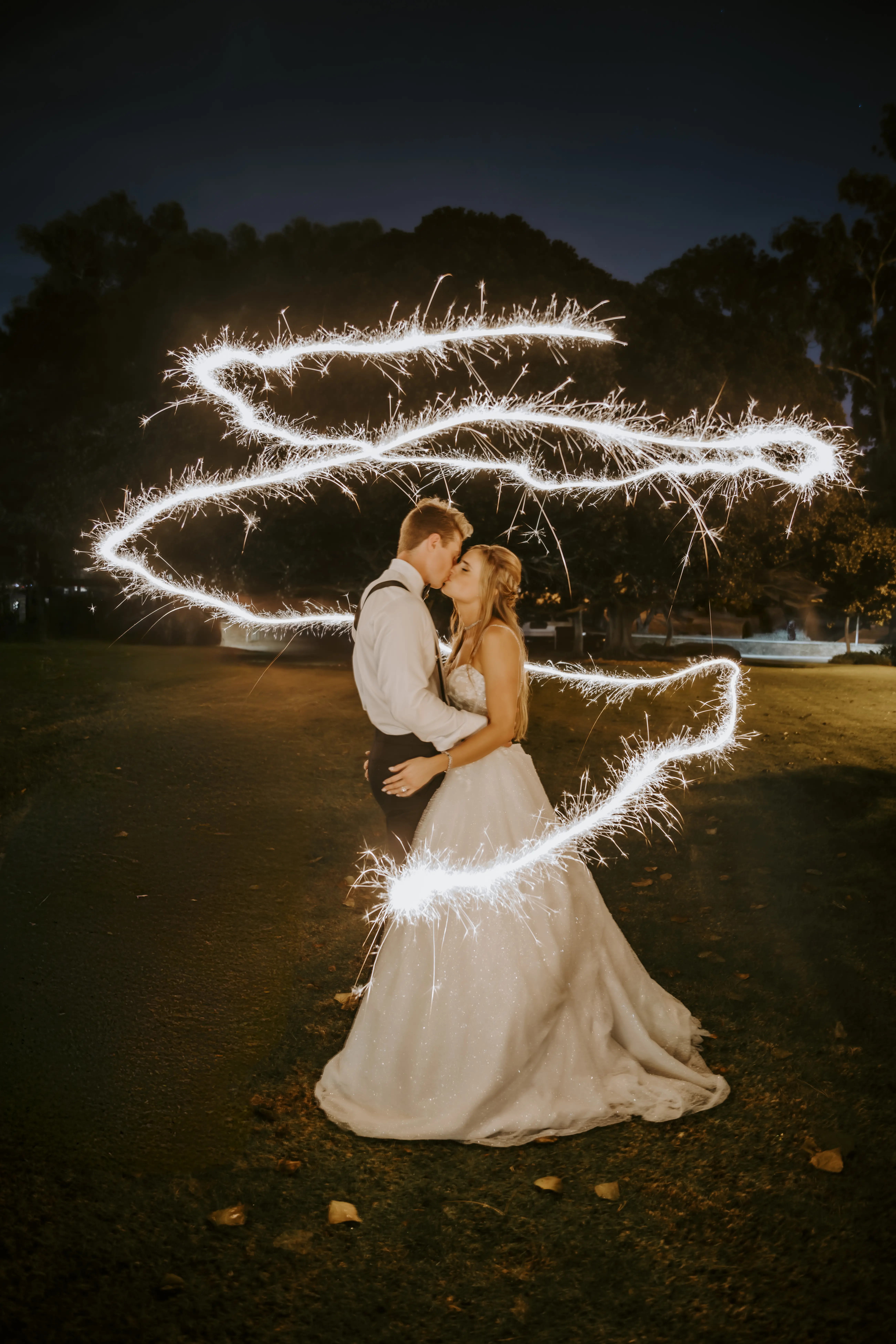 Bride Wearing Sparkly Ballgown Wedding Dress Called Shasta By Sottero And Midgley Kissing Groom With Sparklers Surrounding Them